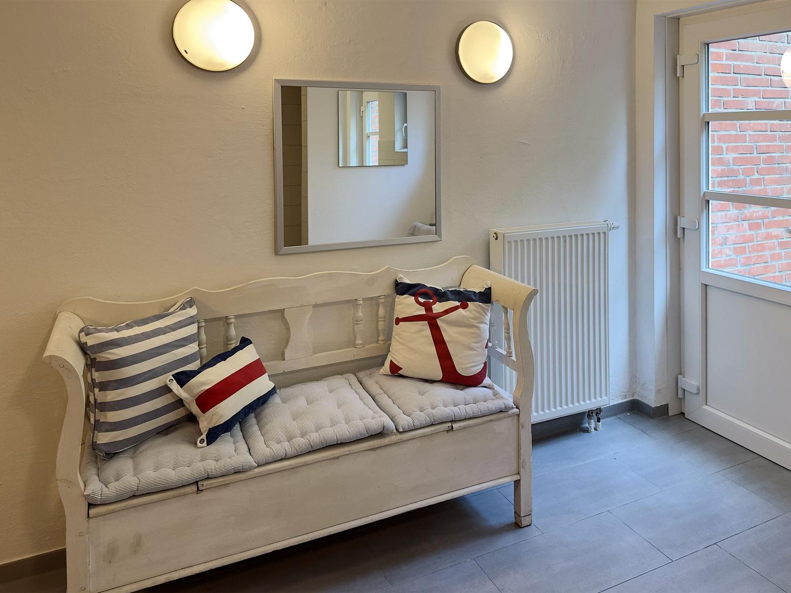 Ein weißer Sessel mit Kissen und einem Spiegel an der Wand.