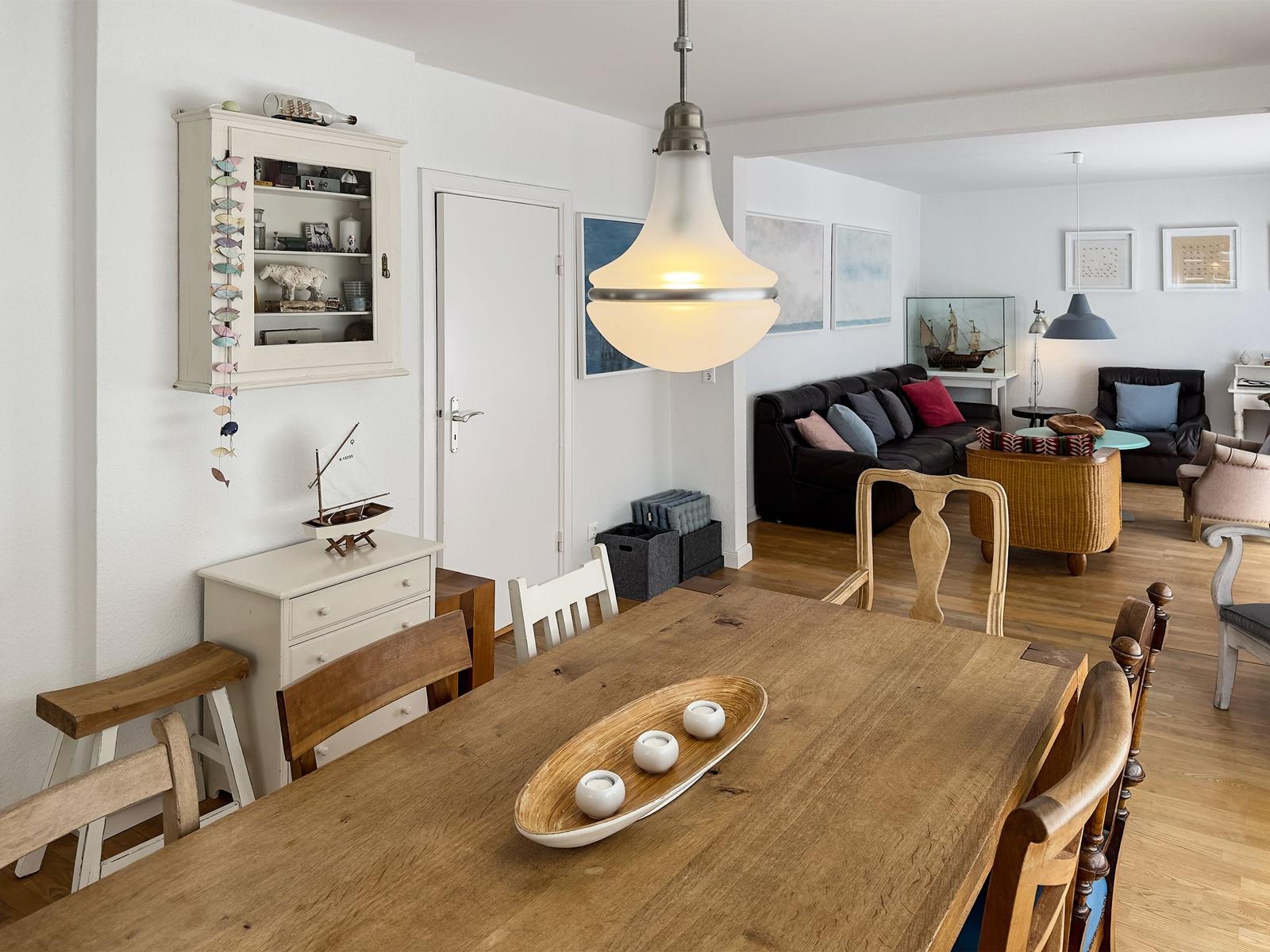 Essbereich mit Holztisch und Stühlen. Wohnbereich mit Sofa und Kamin.
