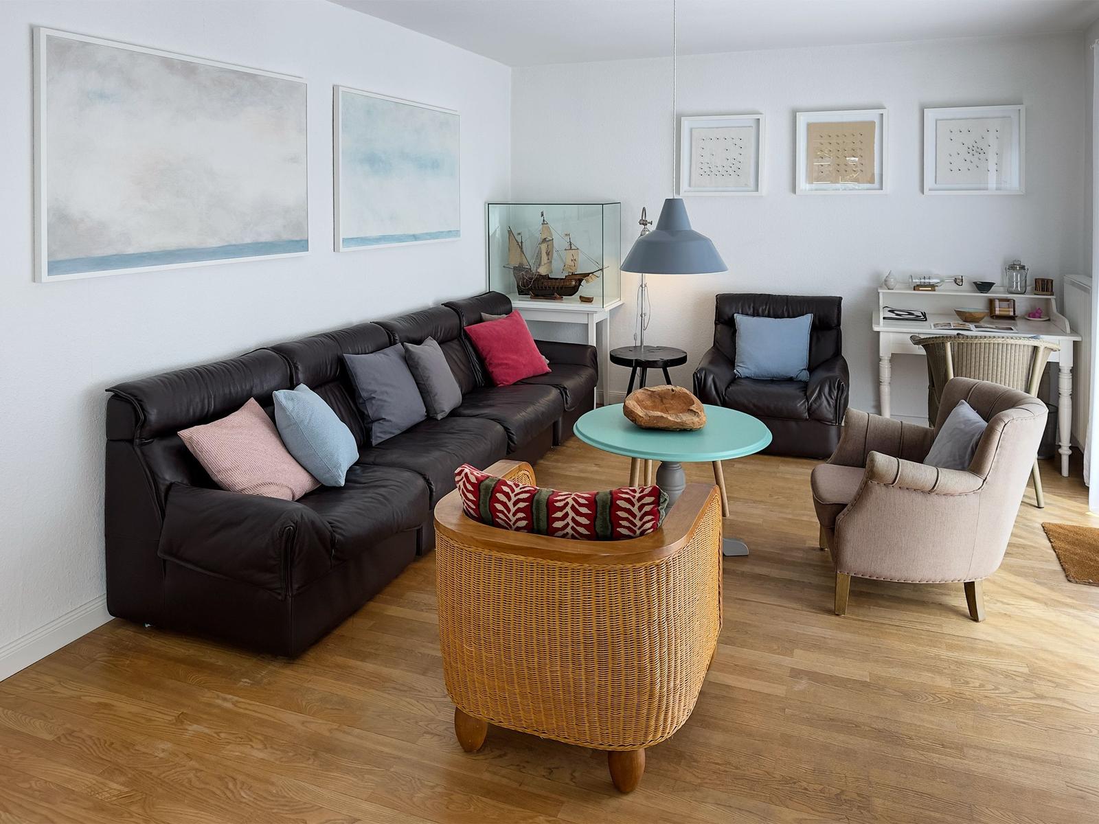 Wohnzimmer mit braunem Sofa, runden Sesseln und Holzboden.