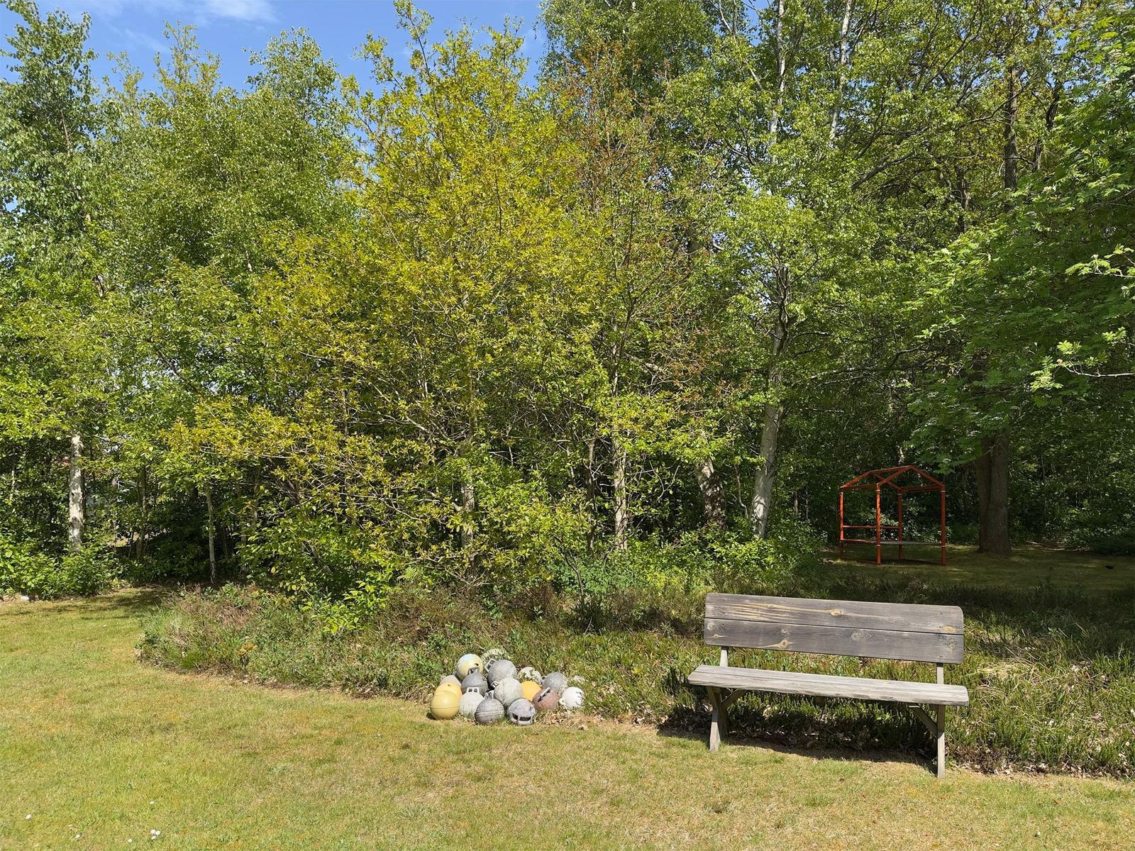 Holzbank und Badekugeln im Garten vor Wald