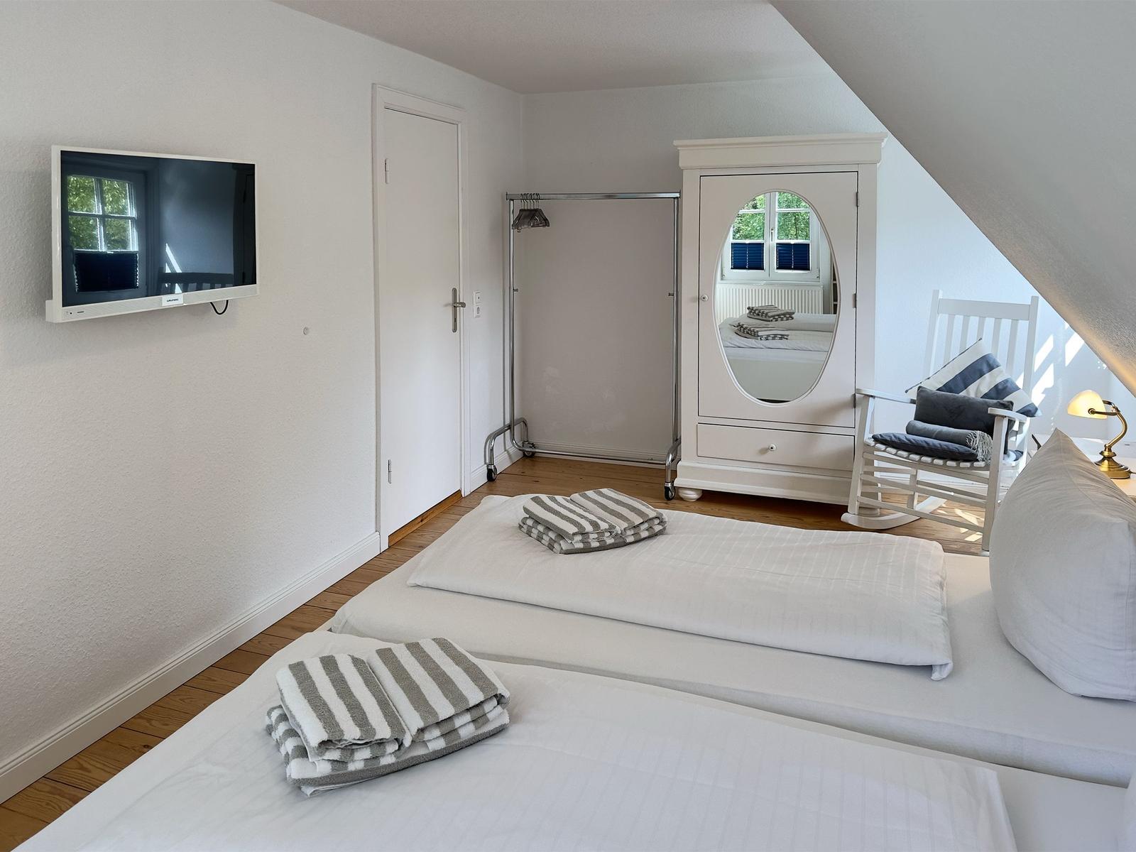 Zimmer mit zwei Betten, Spiegel-Schrank und Fernseher an der Wand.