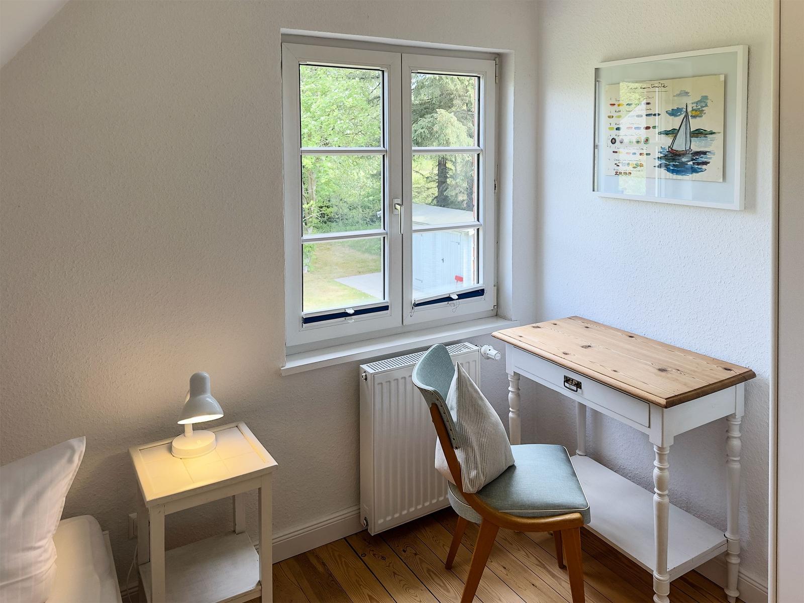 Schreibtisch mit Stuhl und Fensterblick auf Grünflächen