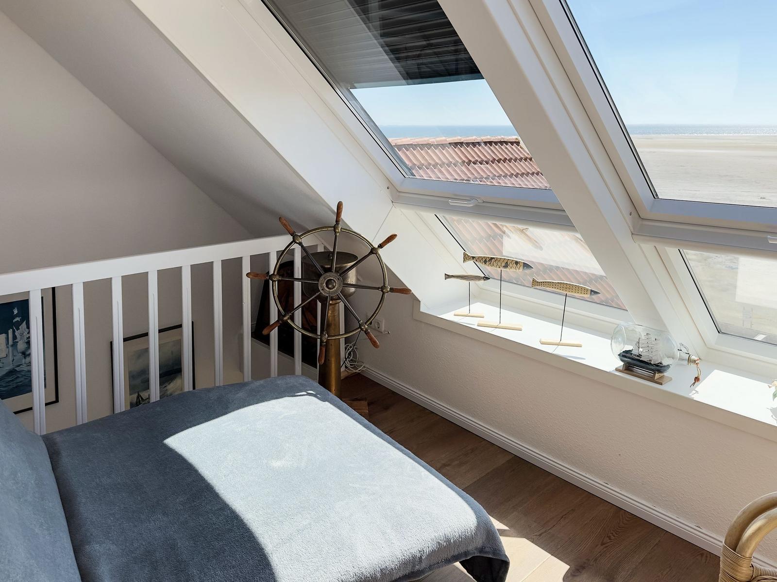 Schlafzimmer mit Dachfenster, Blick auf Strand und Meer, Segelbootmodell und Ruder