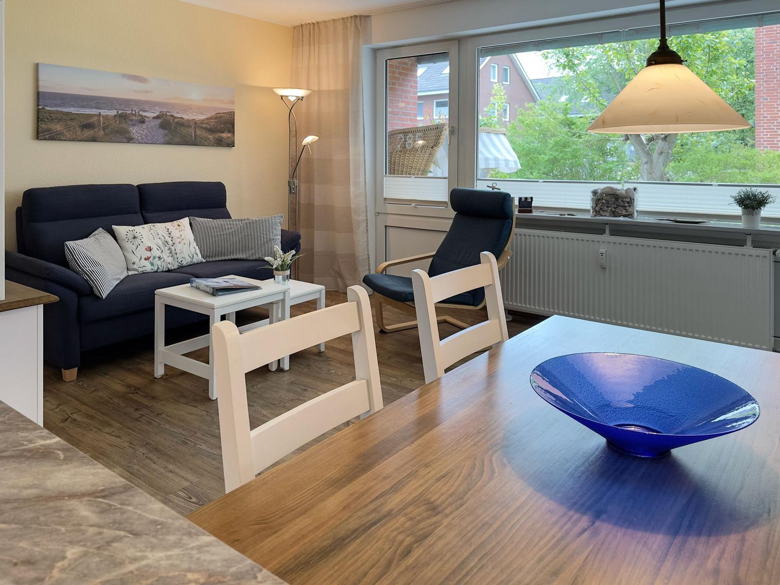Ein Wohn- und Essbereich mit Sofa, Stühlen und einem blauen Schale auf dem Tisch.