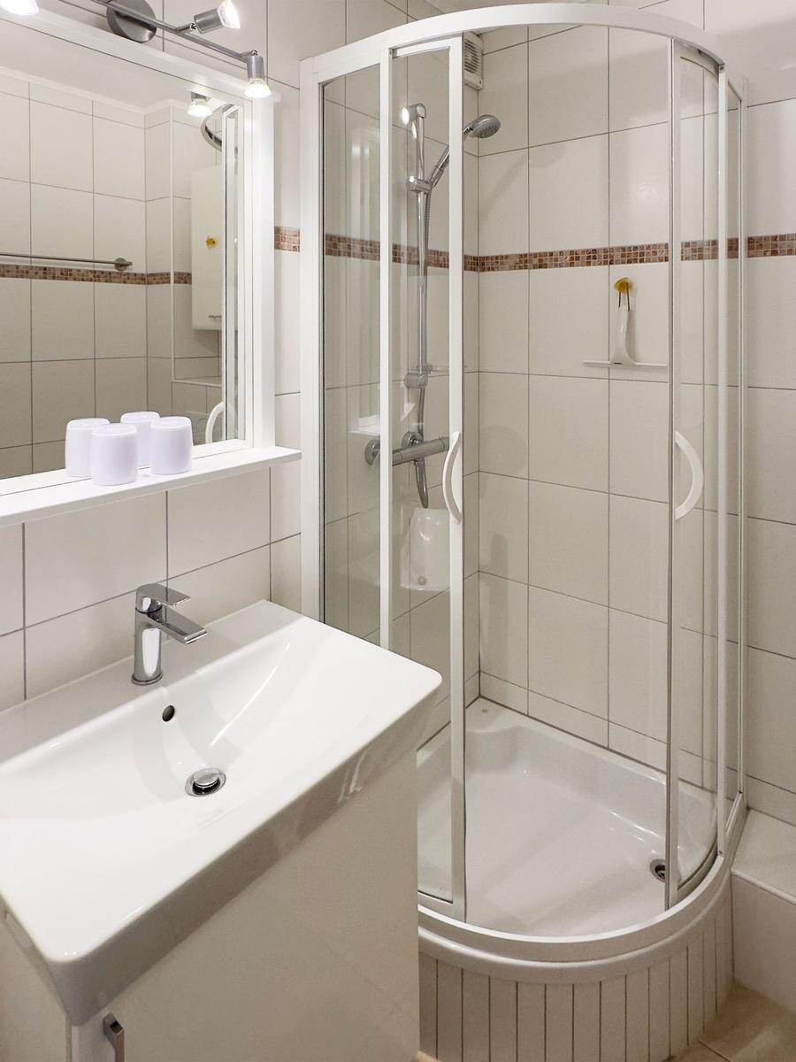 Badezimmer mit Dusche, Waschbecken und Spiegel.