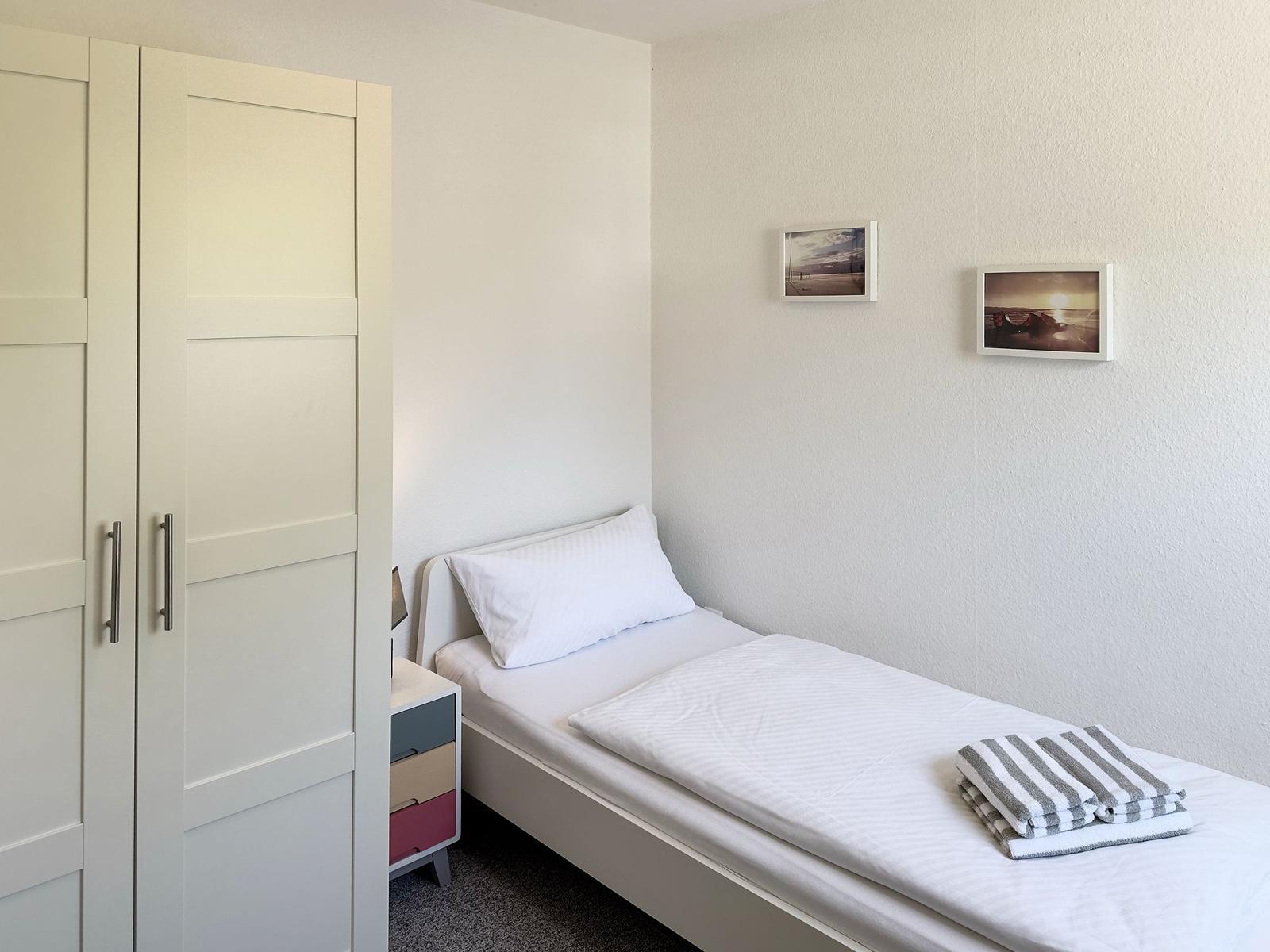 Ein Schlafzimmer mit einem Bett, einem Kleiderschrank und zwei Bildern an der Wand.