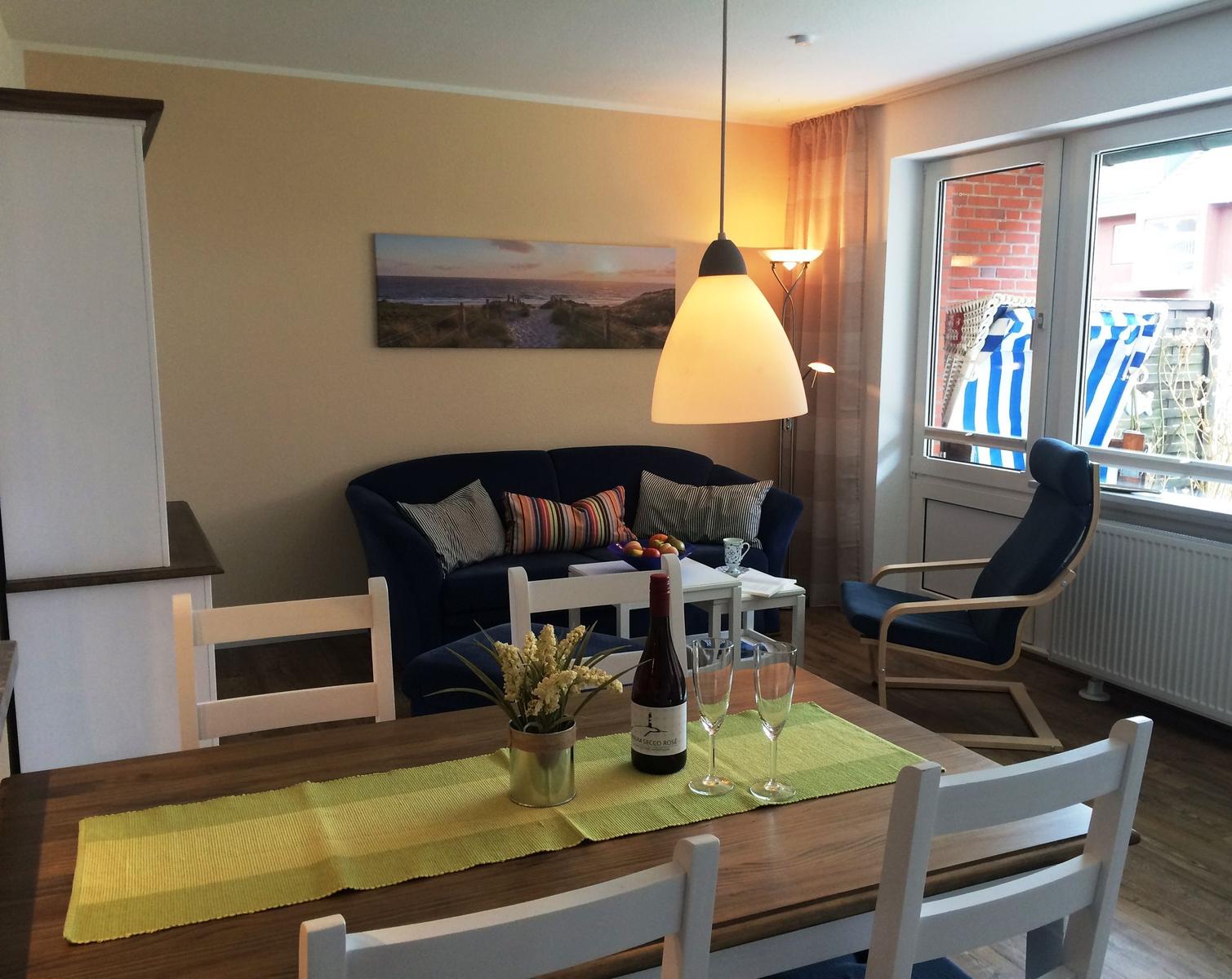 Esszimmer mit Tisch, Stühlen und Sofa. An der Wand hängt ein Strandbild.
