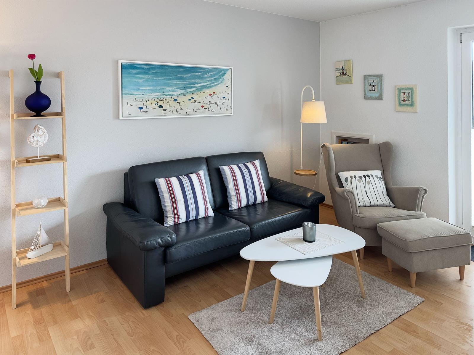 A living room with a black sofa, a gray armchair, and a white coffee table.