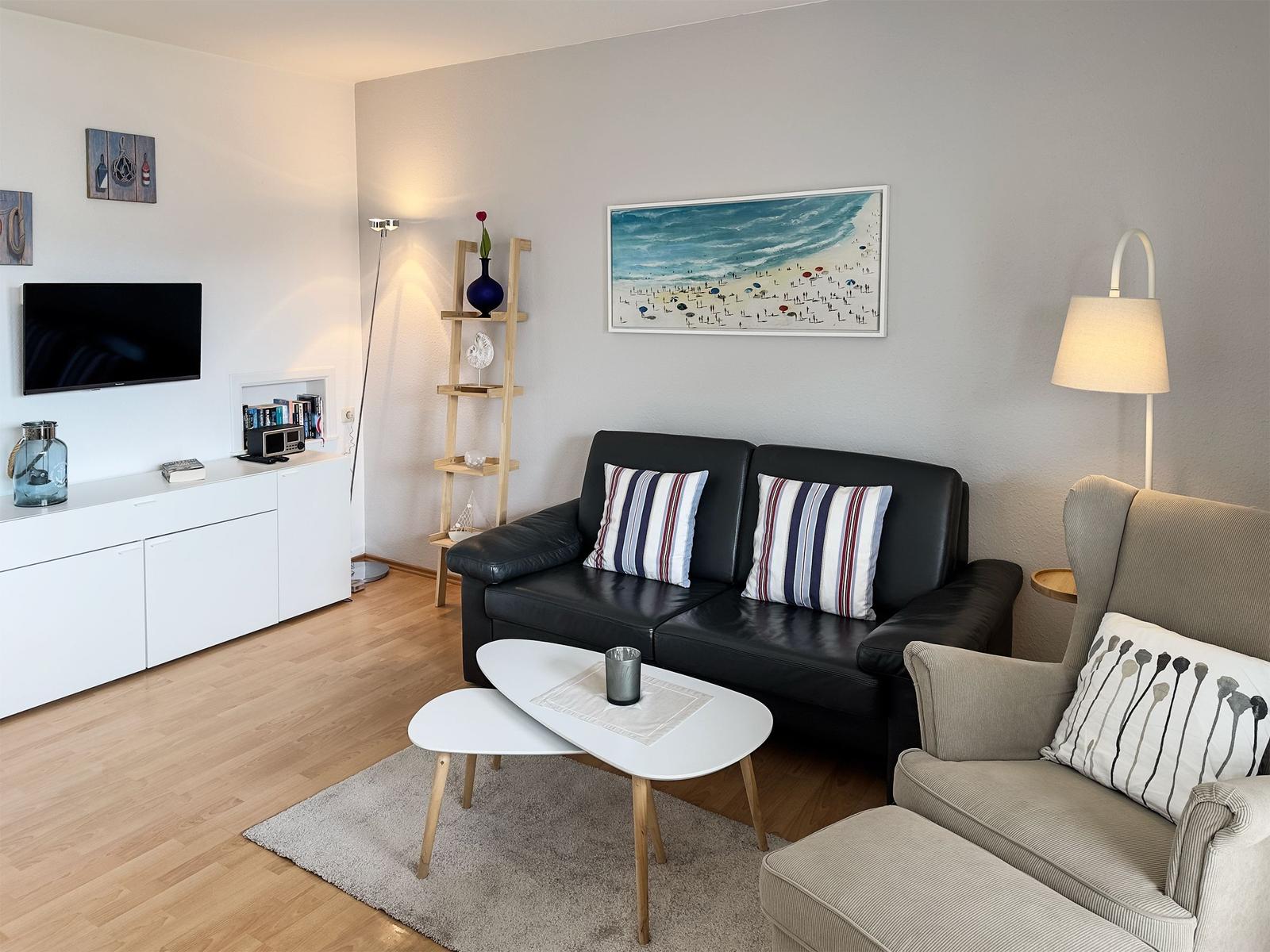Living room with sofa, armchair, coffee table, and TV mounted on wall.