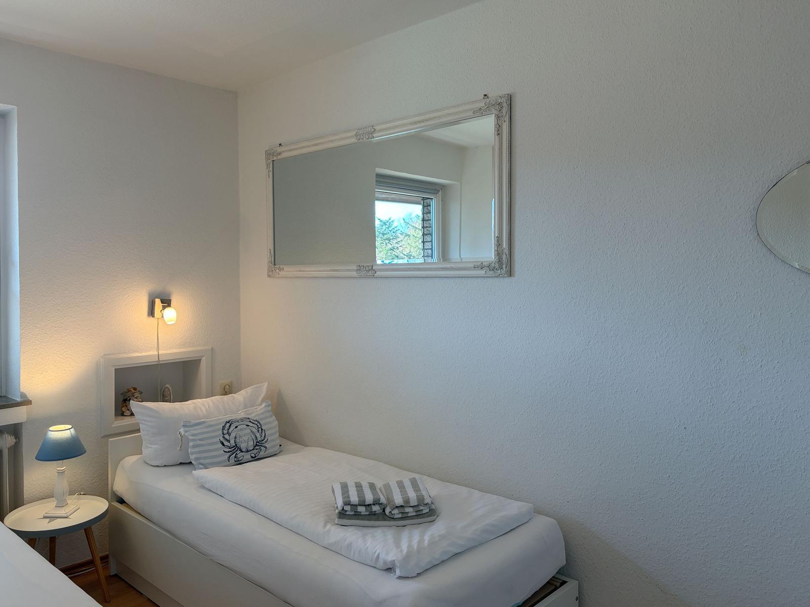 A bedroom with a bed, a mirror, and a lamp.