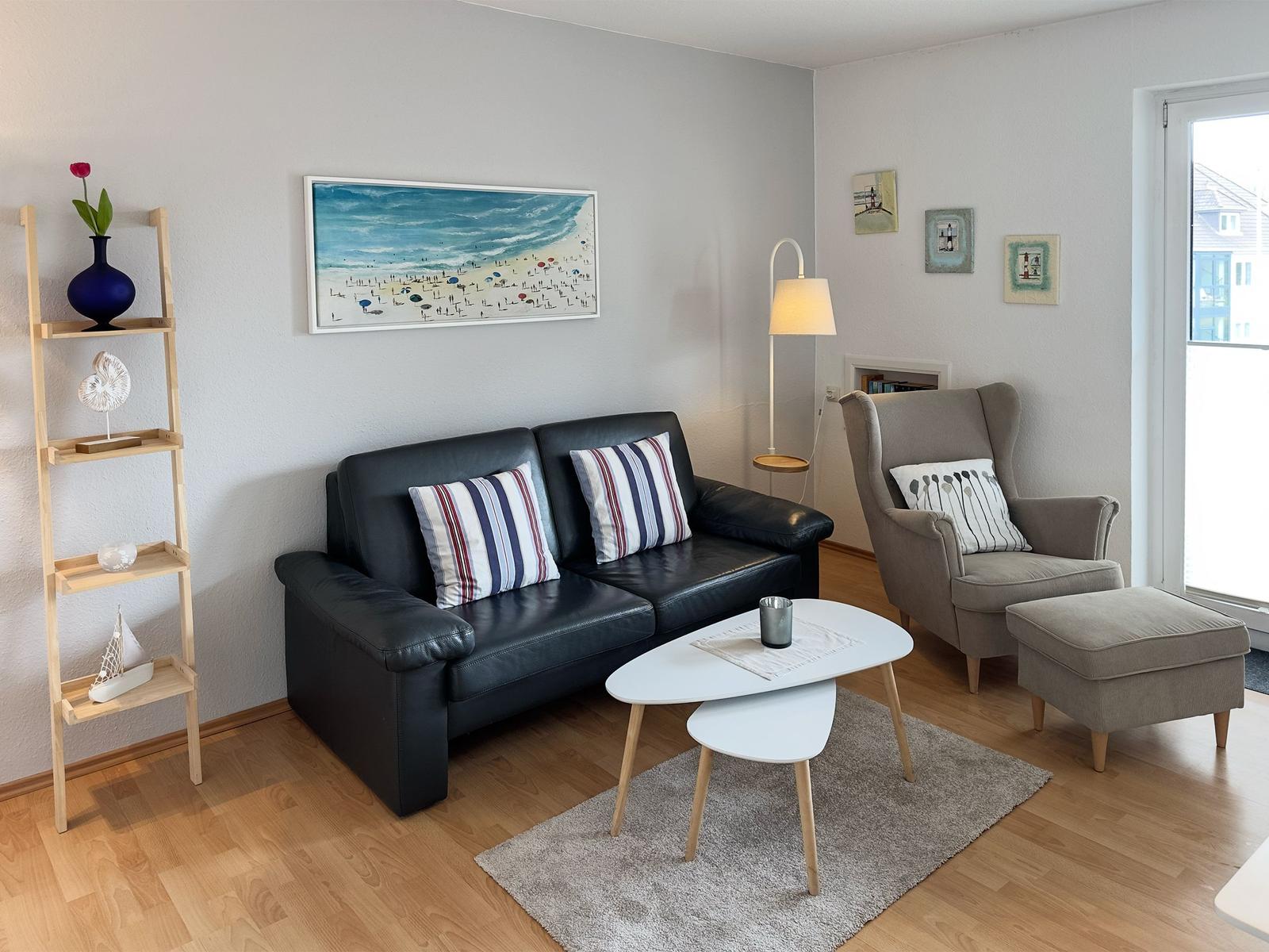 A living room with sofa, armchair, table, and wall art.