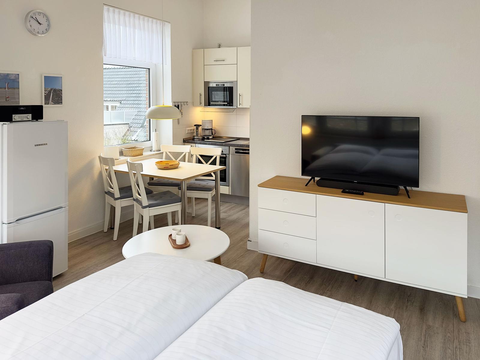 Schlafzimmer mit TV, Küchenbereich und Esstisch. Modern eingerichtet.