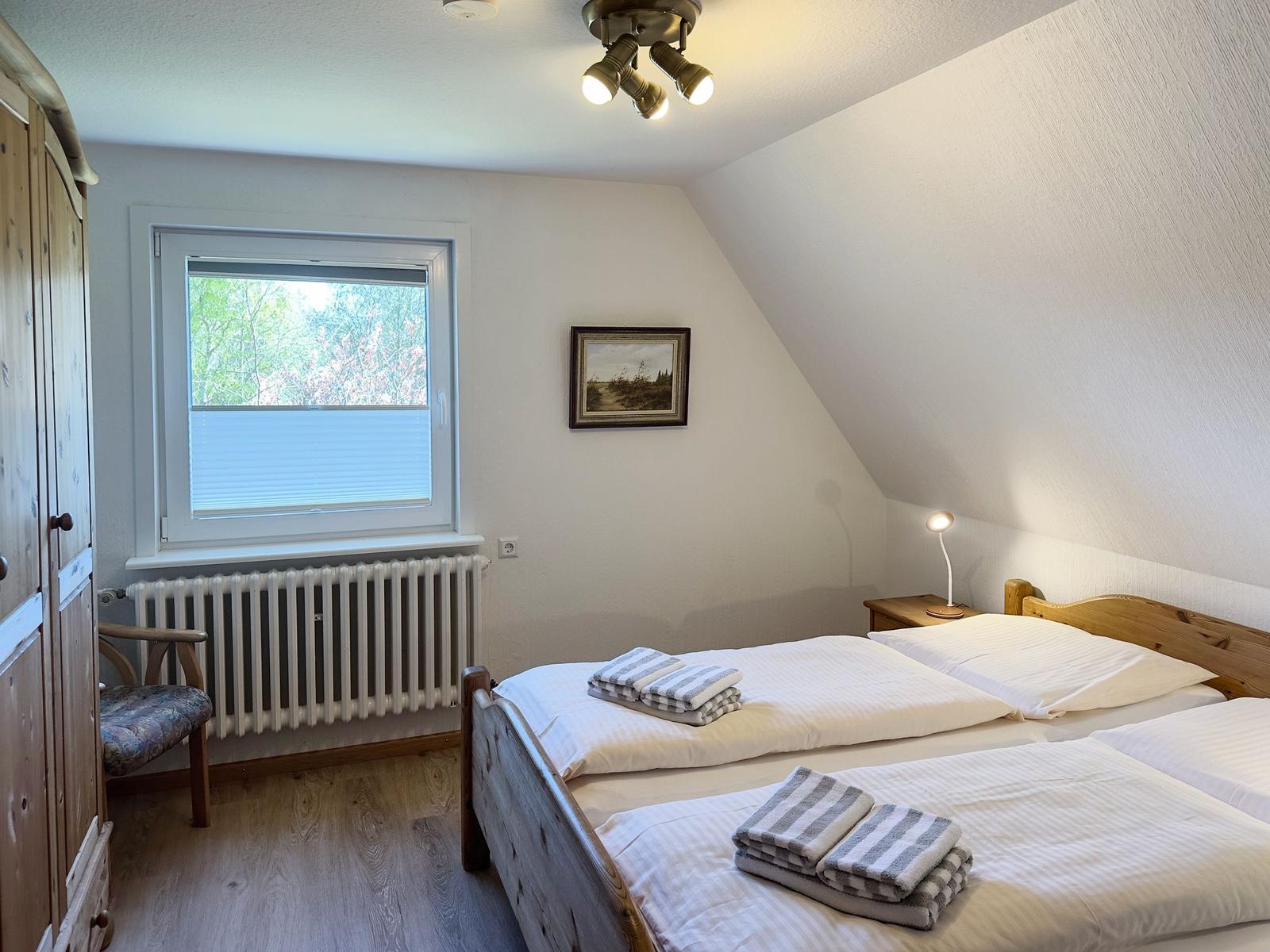 Schlafzimmer mit Doppelbett, Fenster und Holzmöbel