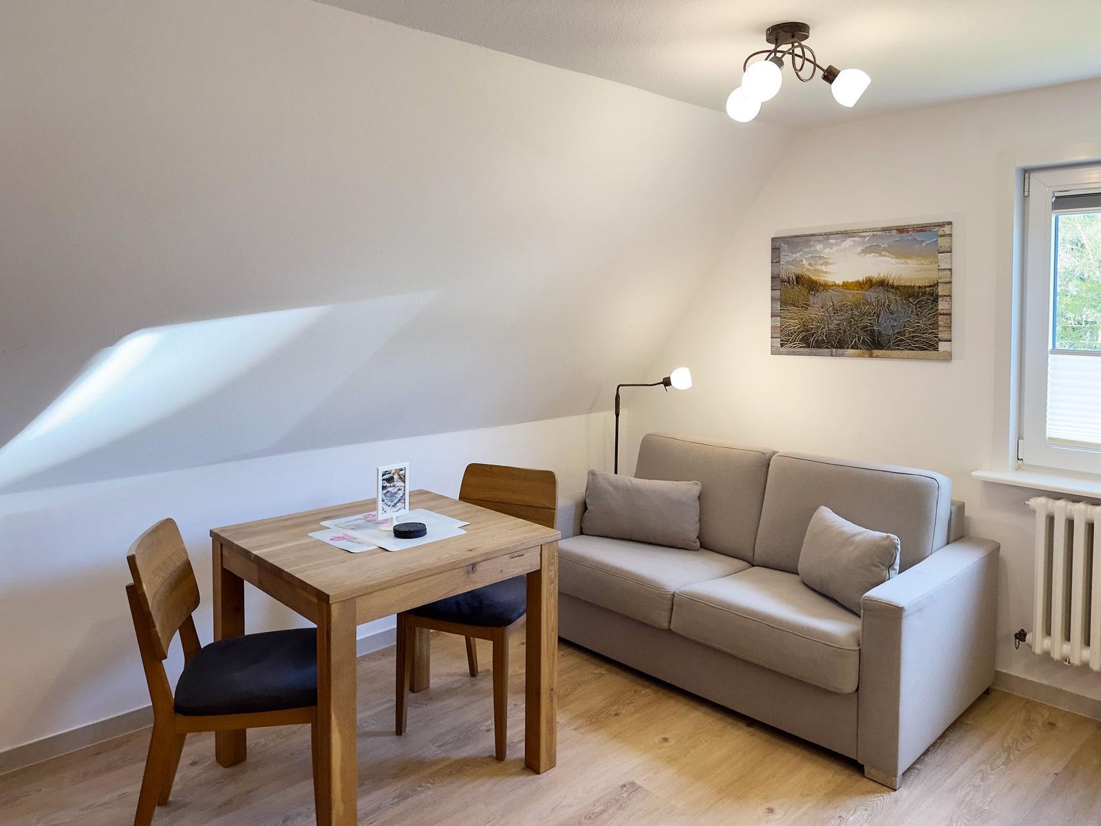 Wohnbereich mit Sofa, Esstisch und Stühlen unter schräger Decke.