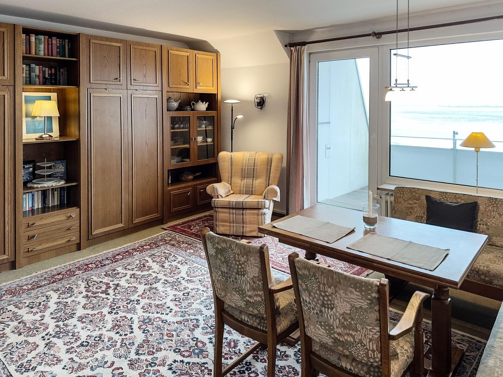 A room with dining area, bookcase, and seating with sea view.