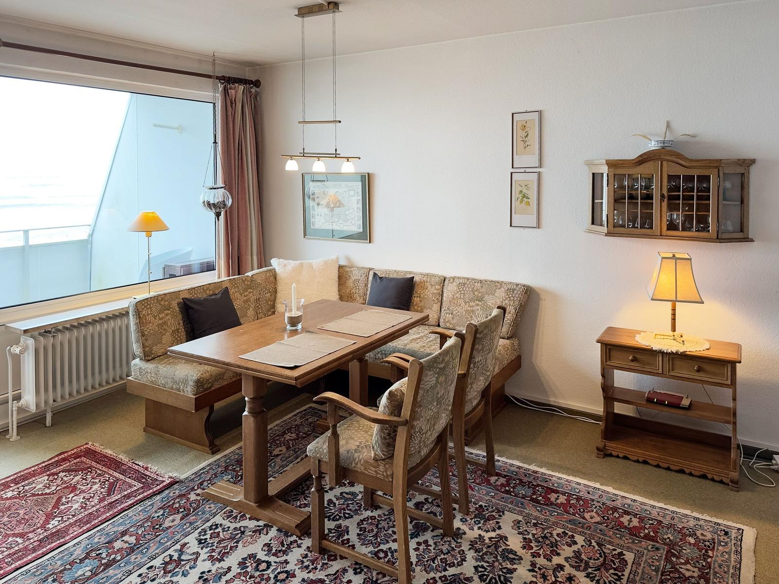 Dining room with wooden table, bench, chairs, rug, and wall art.