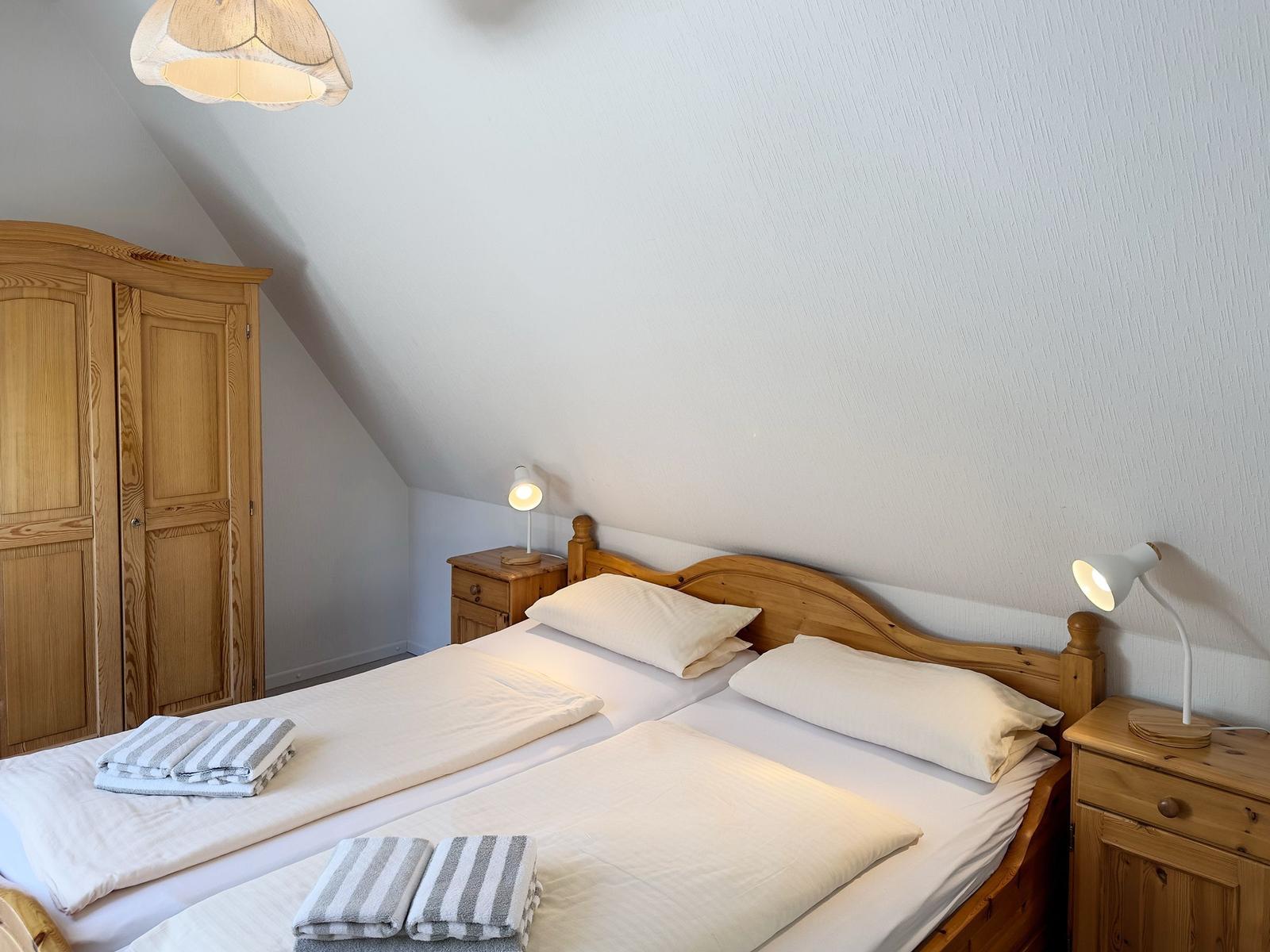Schlafzimmer mit Doppelbett, Holzmöbel und Nachttischen mit Lampen.