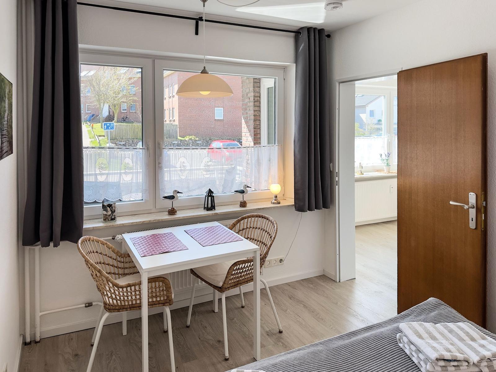 A room with a table, two chairs, and a window with a view outside.