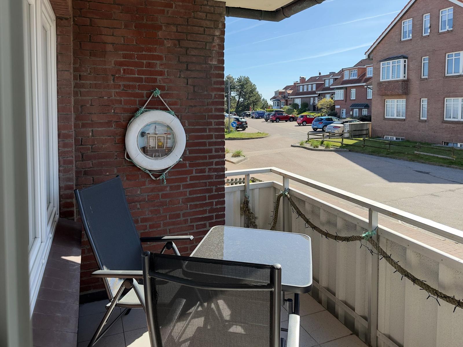 Balcony with table, two chairs, and a lifebuoy on the wall.