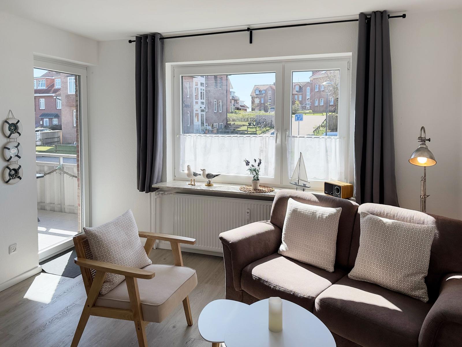Living room with sofa, chair, and view of residential area.
