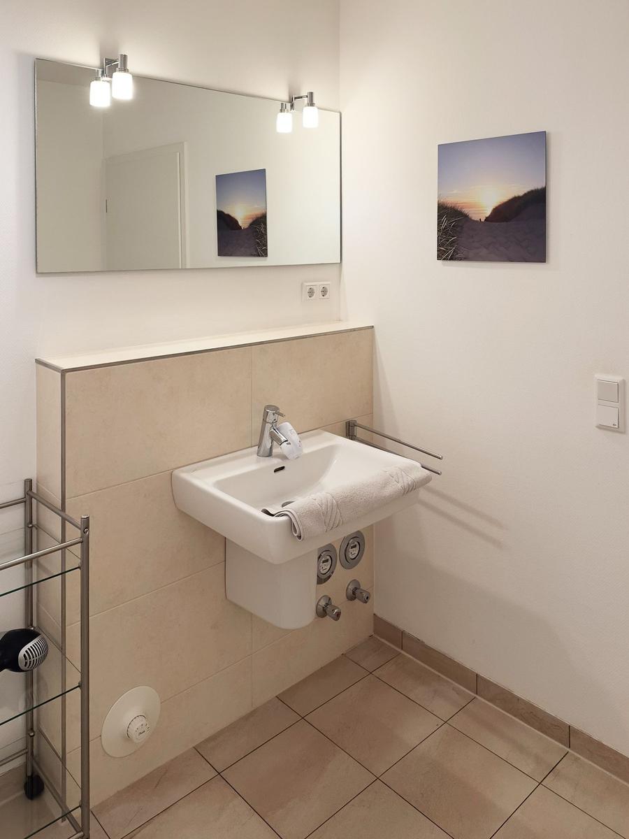 Badezimmer mit Waschbecken, Spiegel und Wandbild