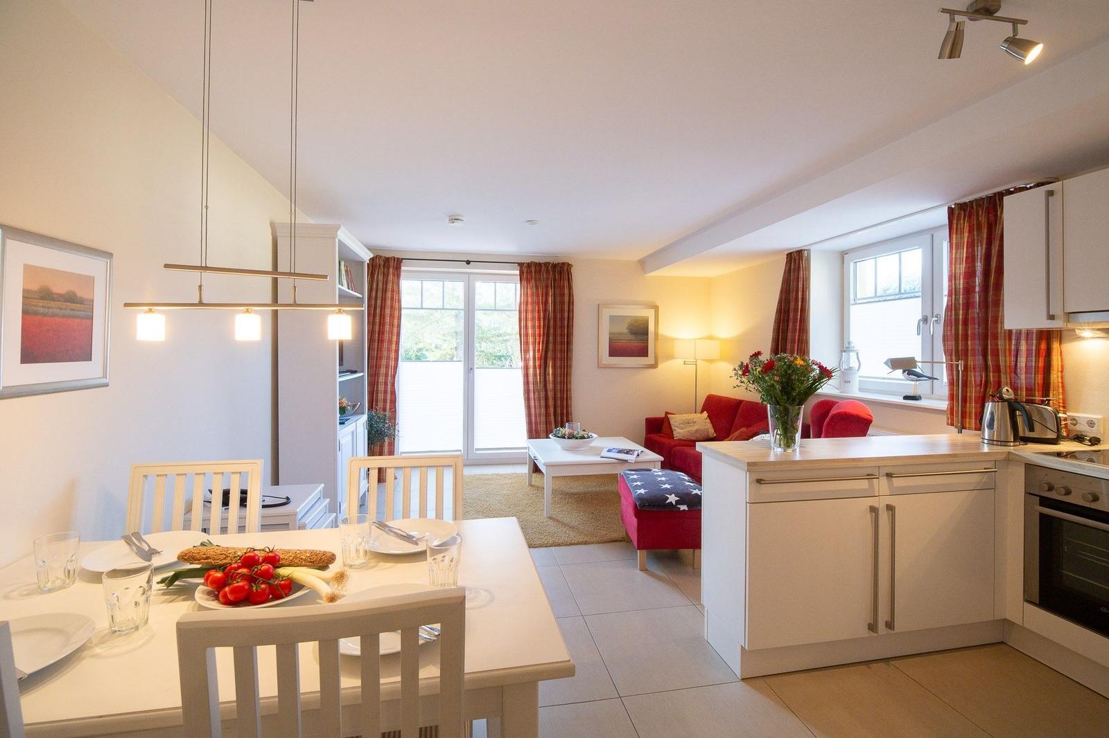 Küche mit Essbereich und Wohnzimmer mit rotem Sofa und Fenster