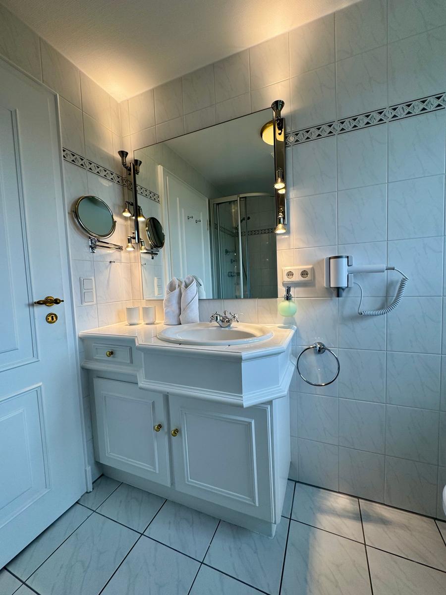 Badezimmer mit Waschbecken, Spiegel und Dusche
