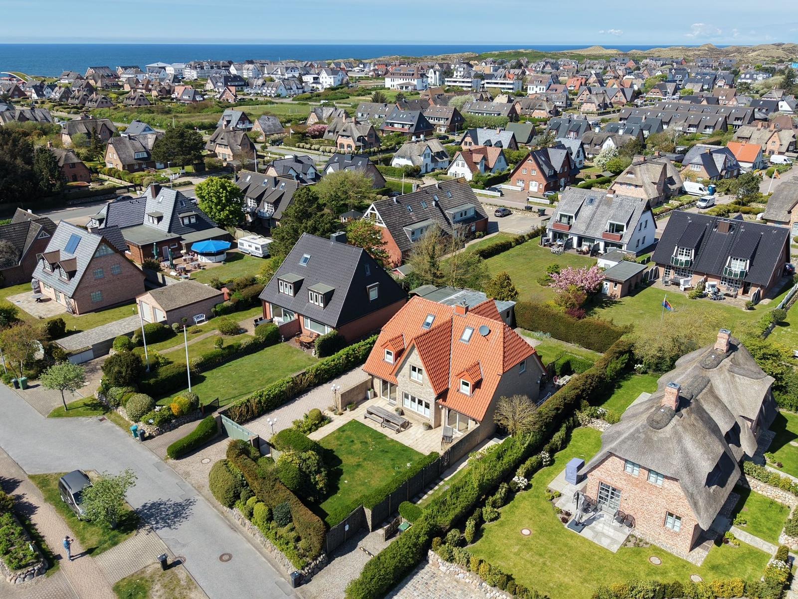 Aerial view of a coastal town with traditional houses and green lawns near the sea.