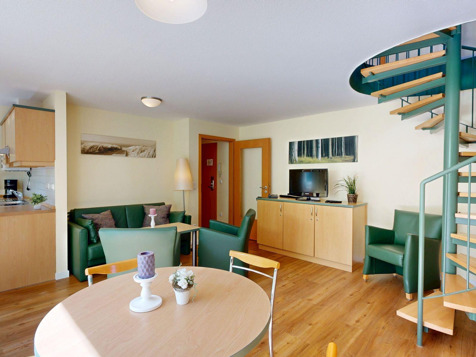 Wohnung mit Essbereich, Sofa, Fernseher und Wendeltreppe.