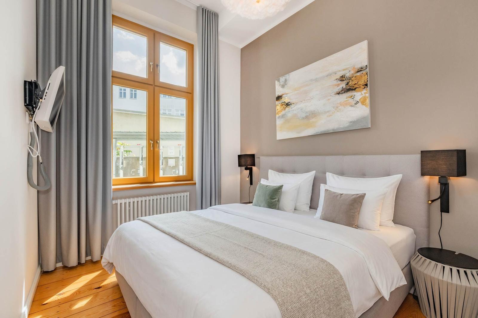 Schlafzimmer mit Bett, Fenster und Wandbild. Holzboden und moderne Beleuchtung.