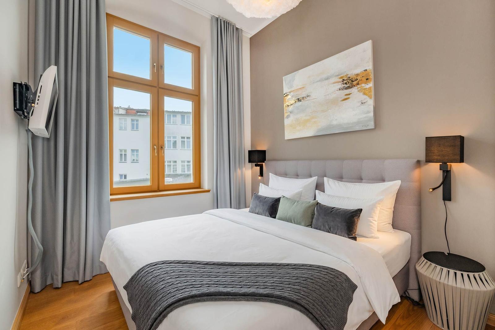 Schlafzimmer mit großem Bett, Fenster und Wandbild.