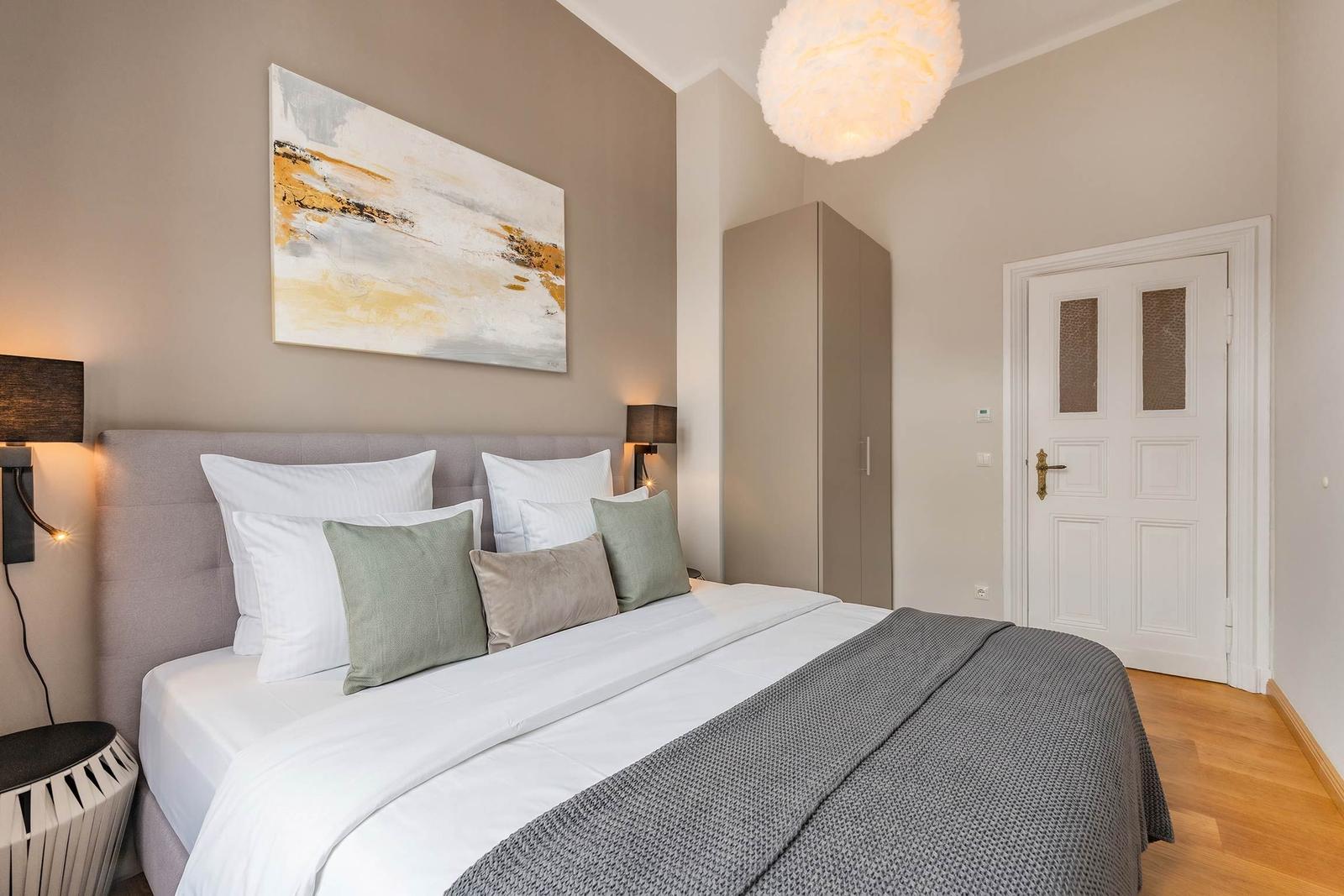 Schlafzimmer mit Bett, Wandbild, Kleiderschrank und Tür.