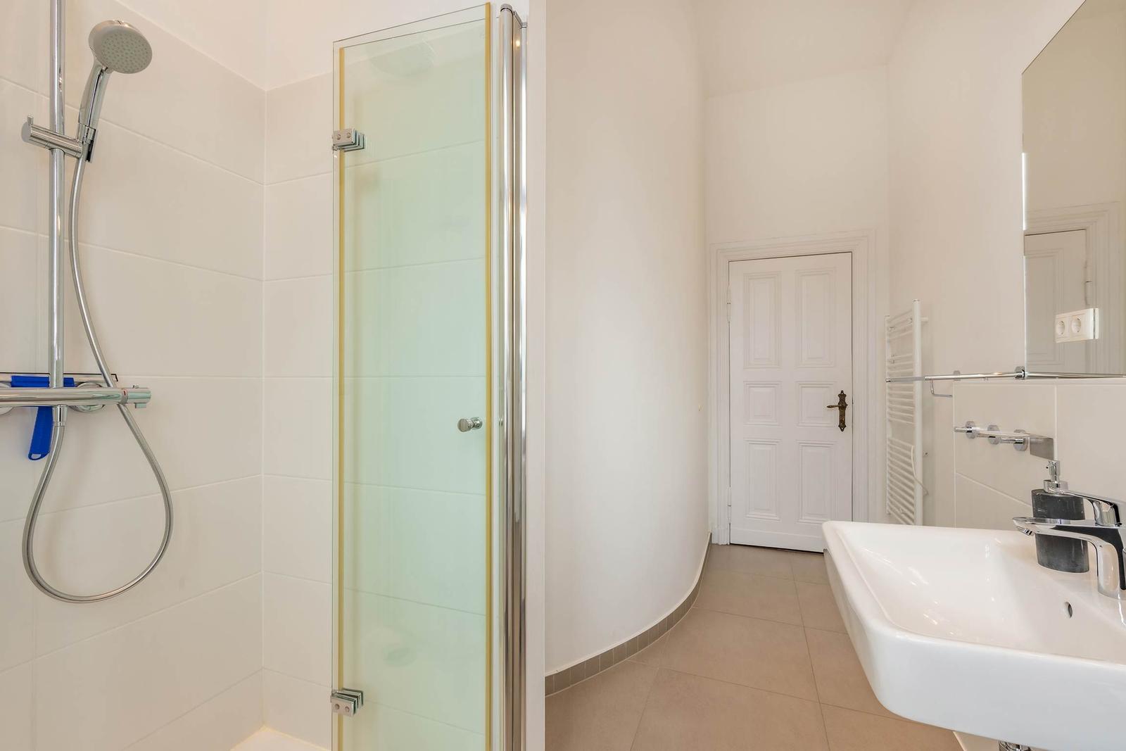 Badezimmer mit Dusche, Waschbecken und Spiegel