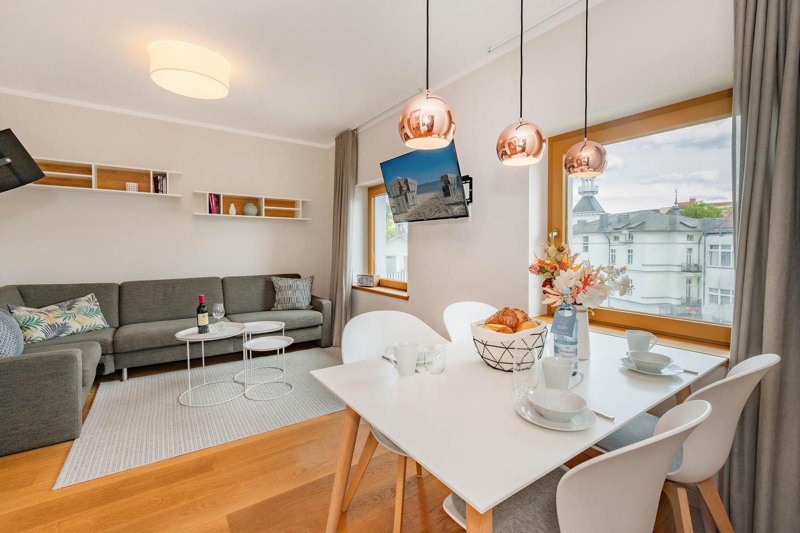 Wohn- und Essbereich mit Sofa, Tisch, Stühlen und Fensterblick.