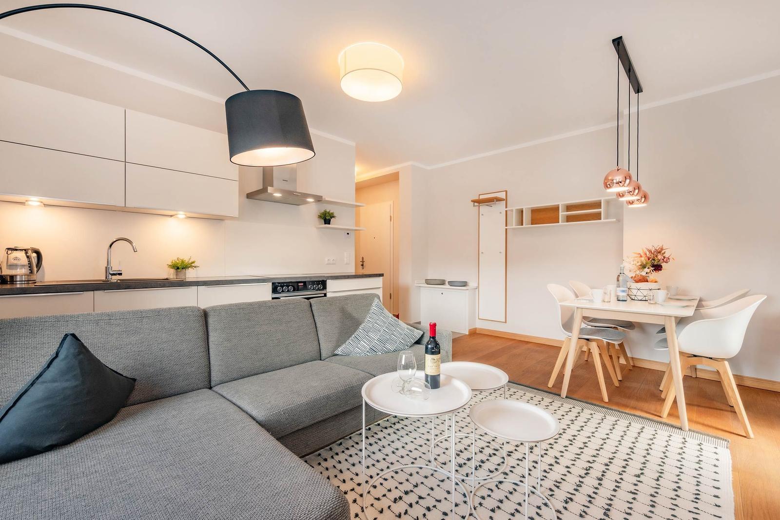 Wohnzimmer mit Sofa, Küchenzeile und Esstisch mit Stühlen.