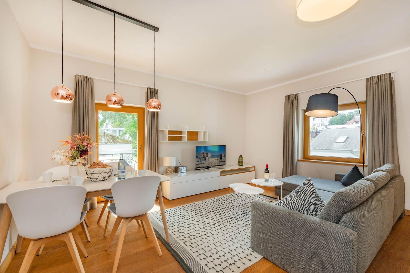 Wohn- und Essbereich mit Sofa, TV und Esstisch mit Stühlen.