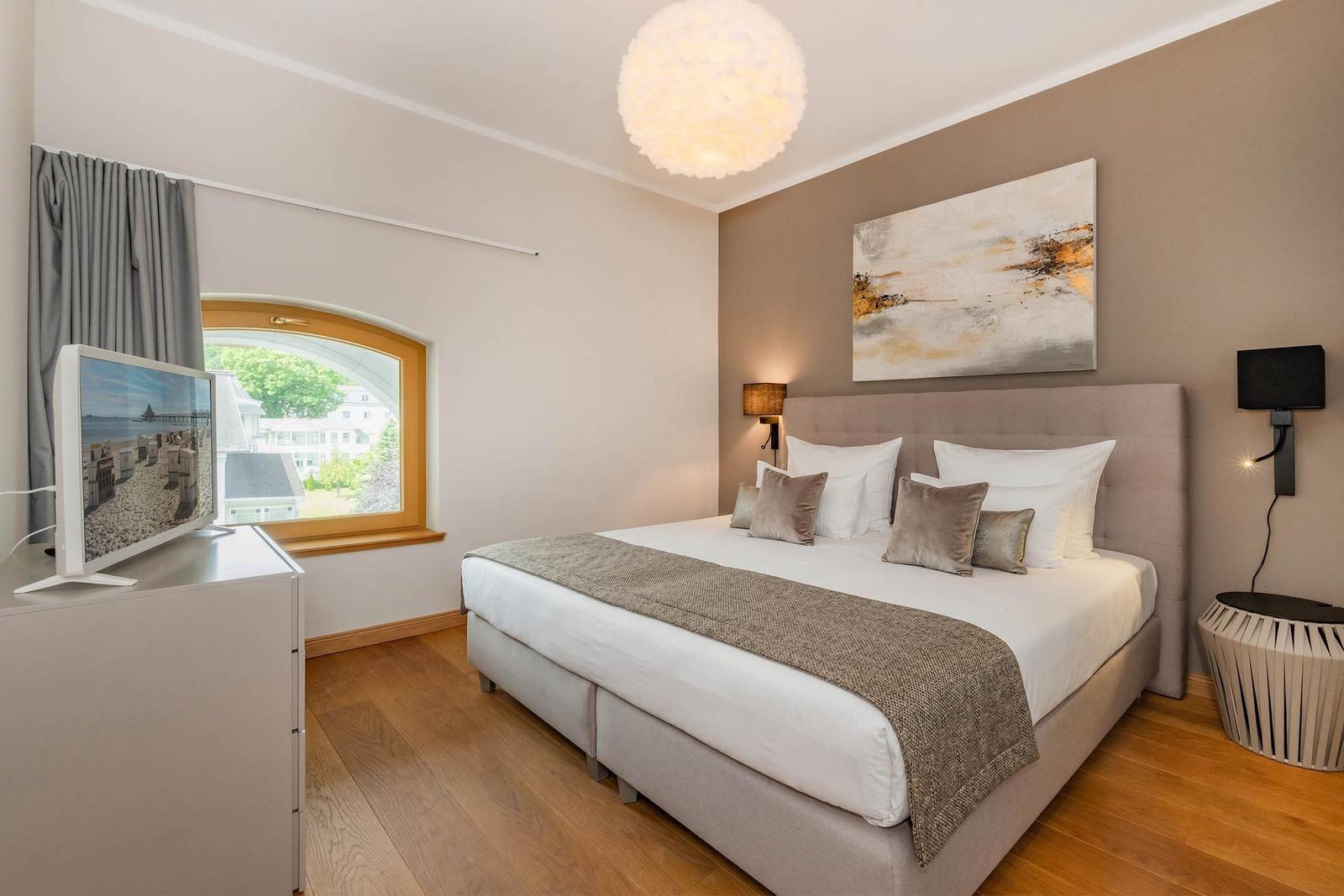 Schlafzimmer mit Bett, Fenster und Fernseher.