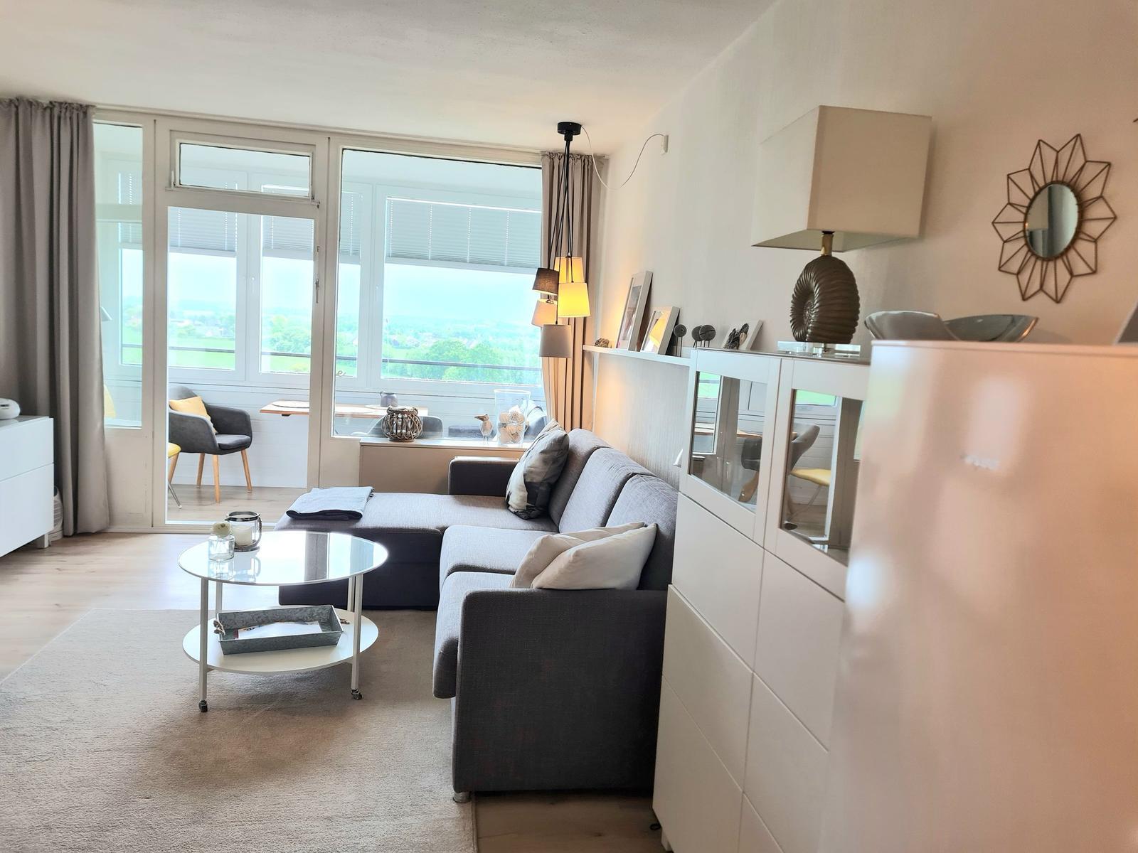Wohnzimmer mit Sofa, Couchtisch und Blick auf Balkon.