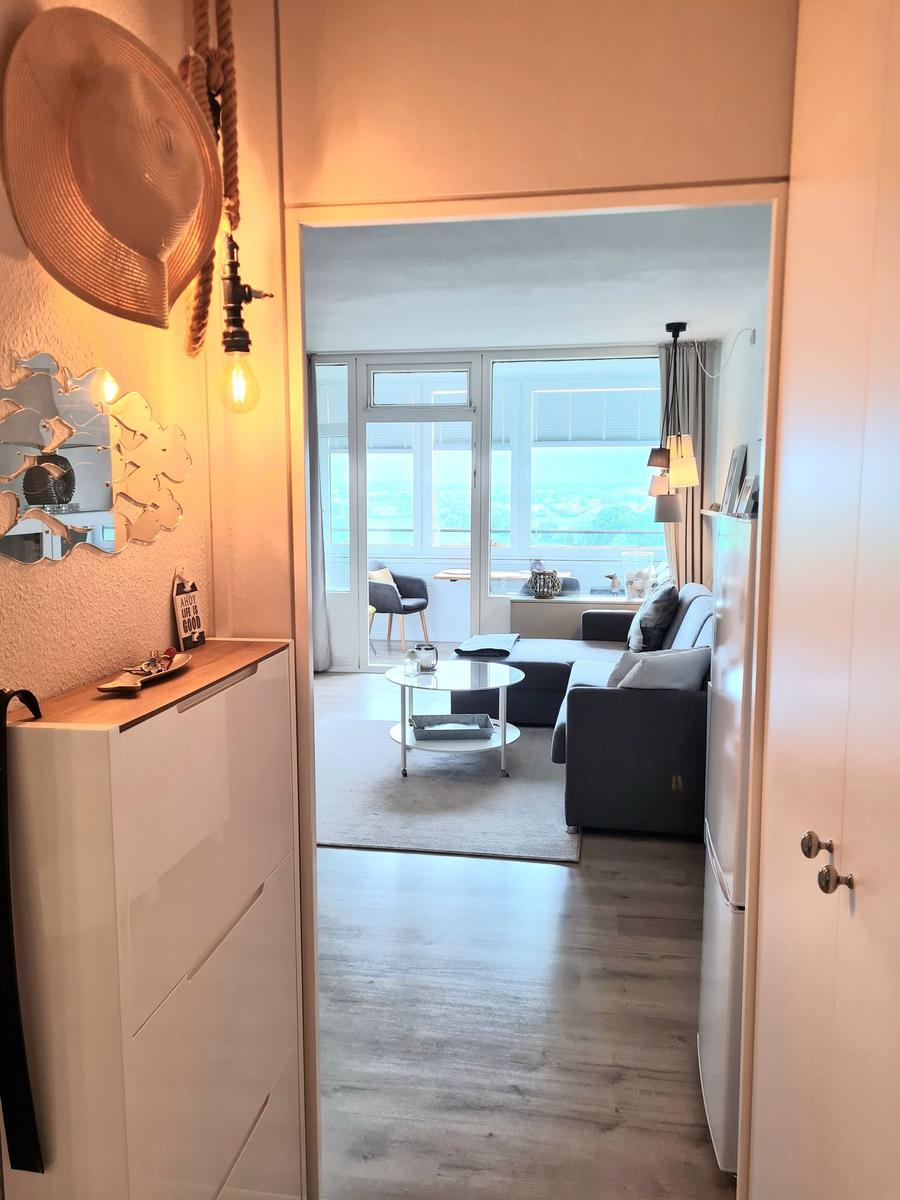 Wohnung mit Blick auf die Stadt. Wohnzimmer mit Sofa, Couchtisch und Balkon.