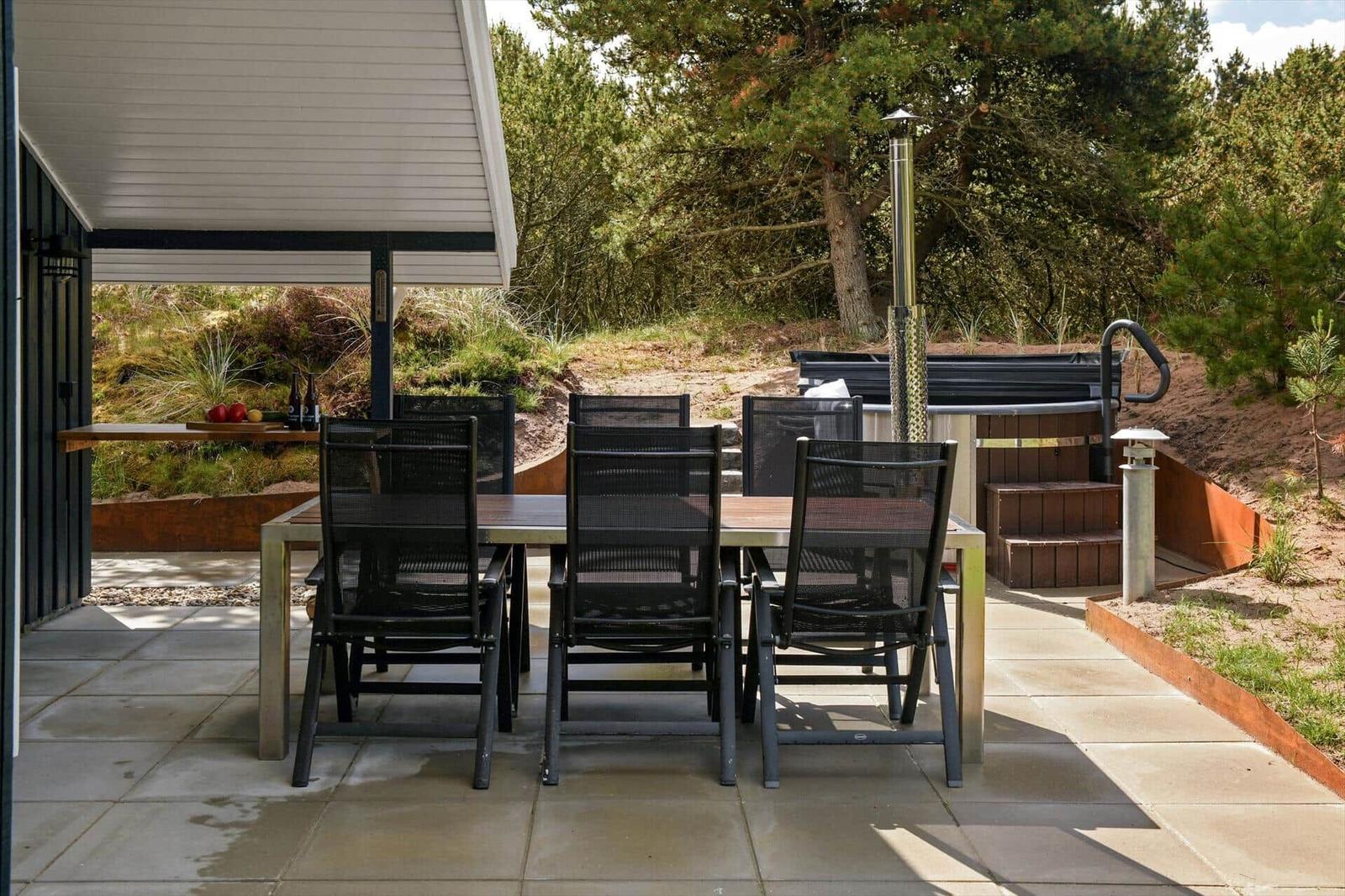 Terrasse mit Tisch, Stühlen und Whirlpool im Grünen