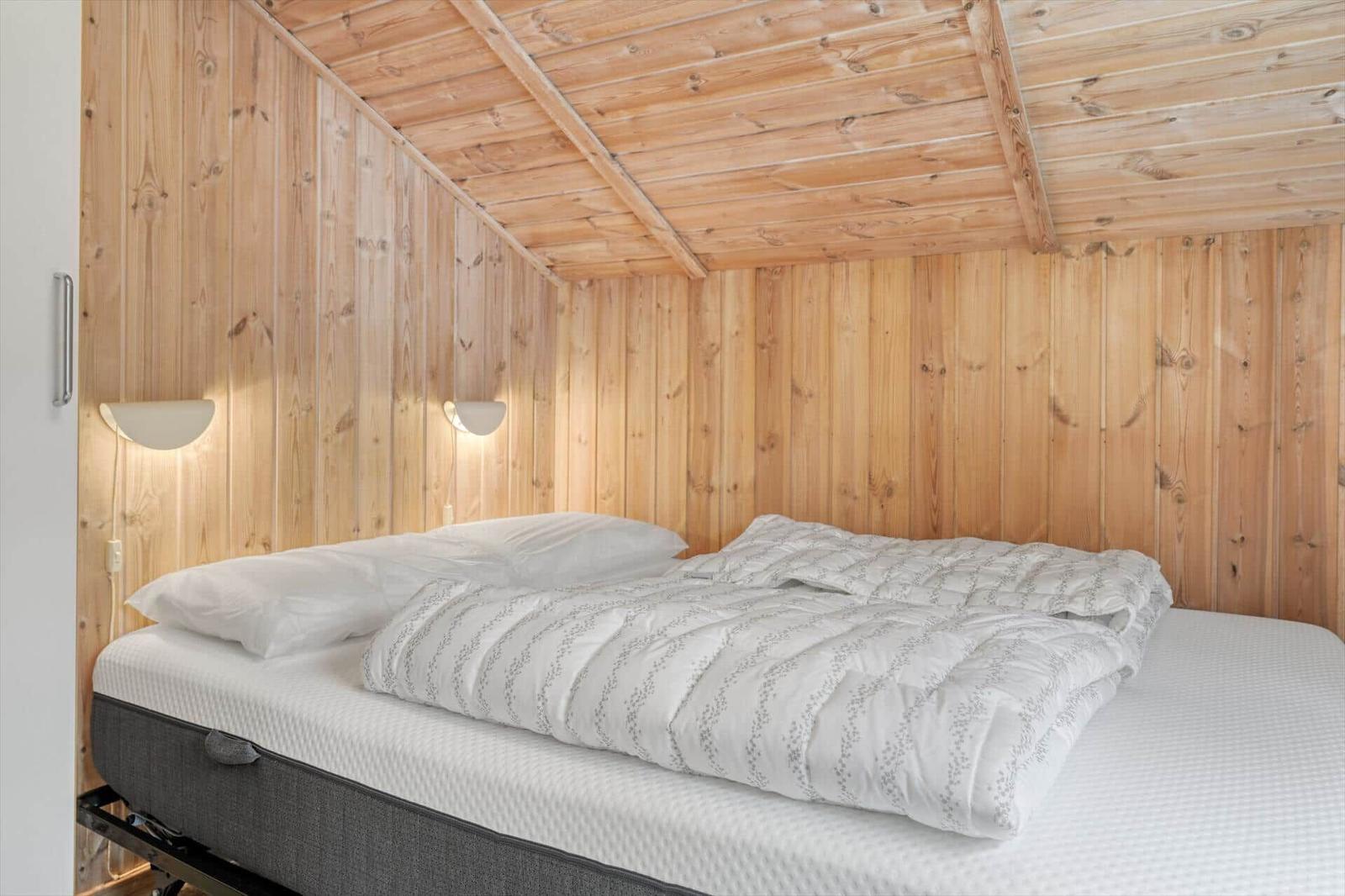 Schlafzimmer mit Holzwänden und Bett mit weißer Bettwäsche.