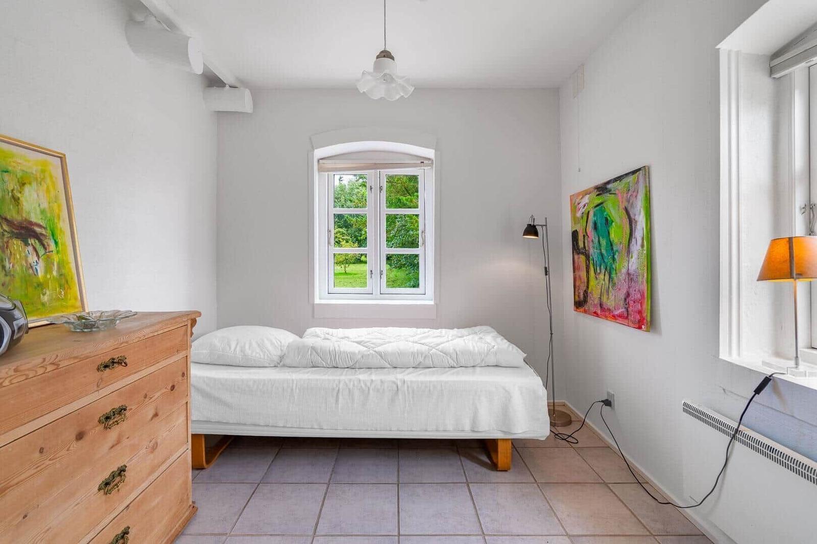Schlafzimmer mit Bett, Schrank und Fenster zum Garten.