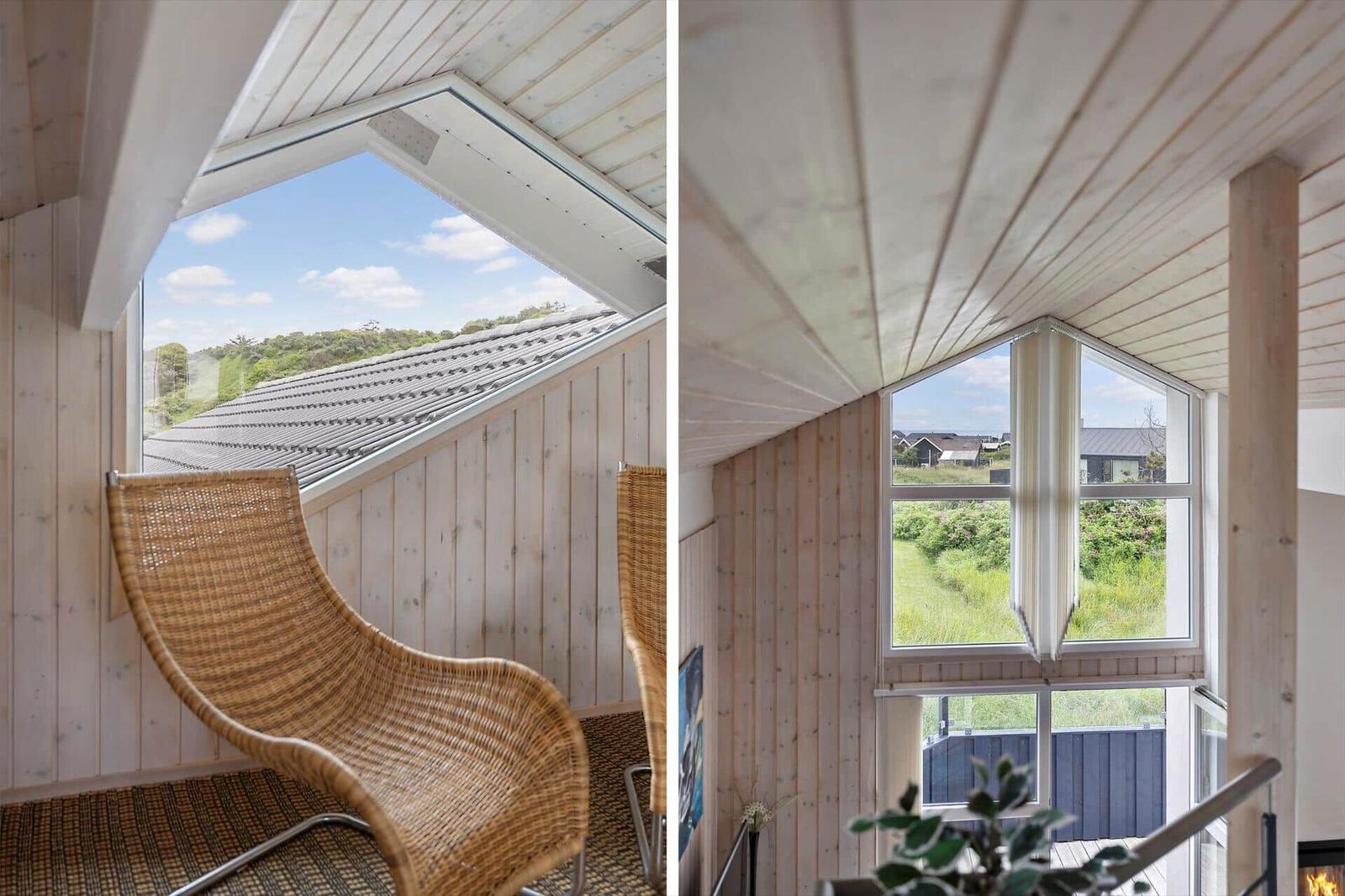 Wohnraum mit Holzwänden und großem Fenster. Blick auf Dach und Grünflächen.