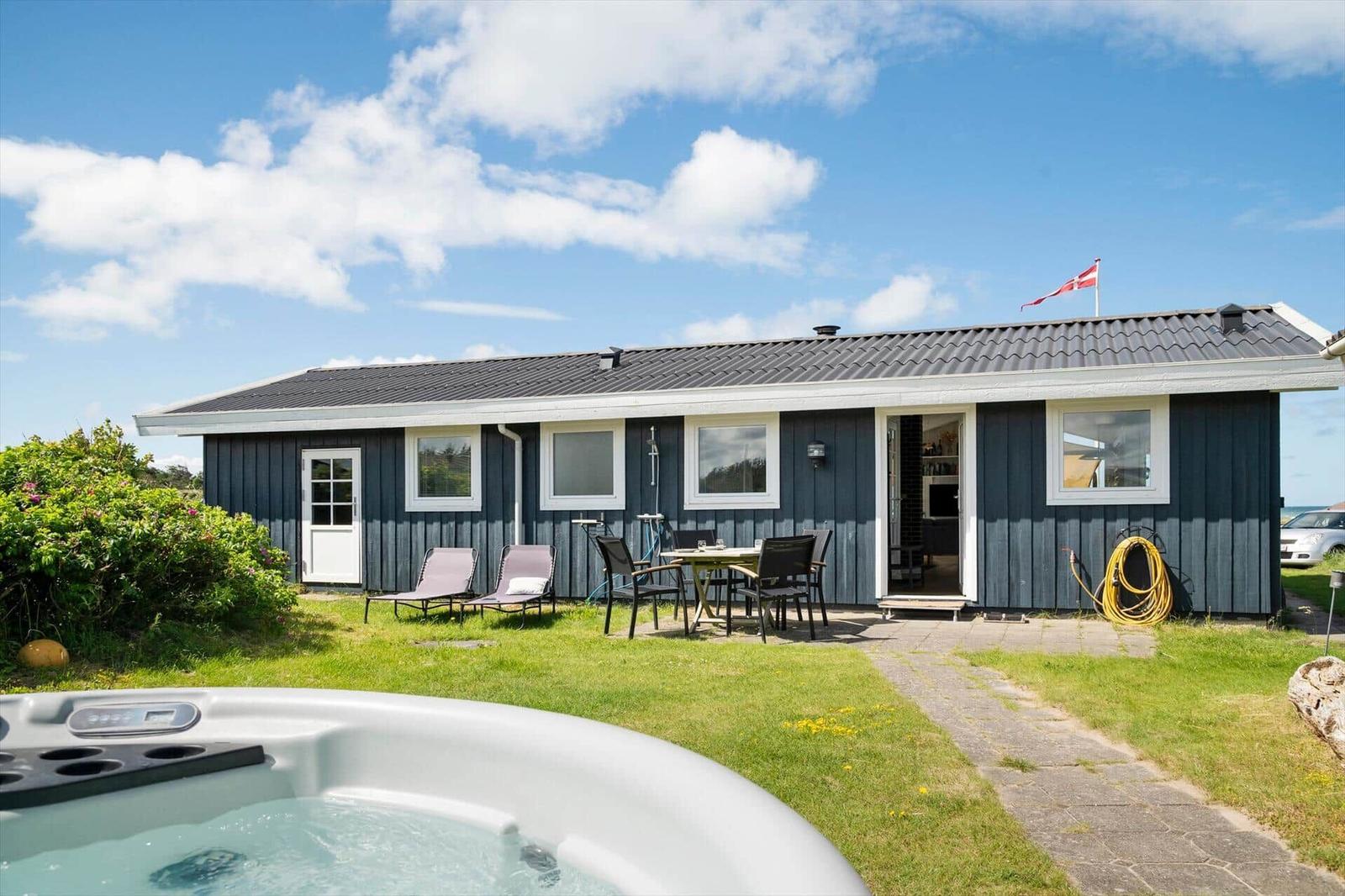 Ein Haus mit Garten, Liegestühlen und einem Whirlpool im Vordergrund.