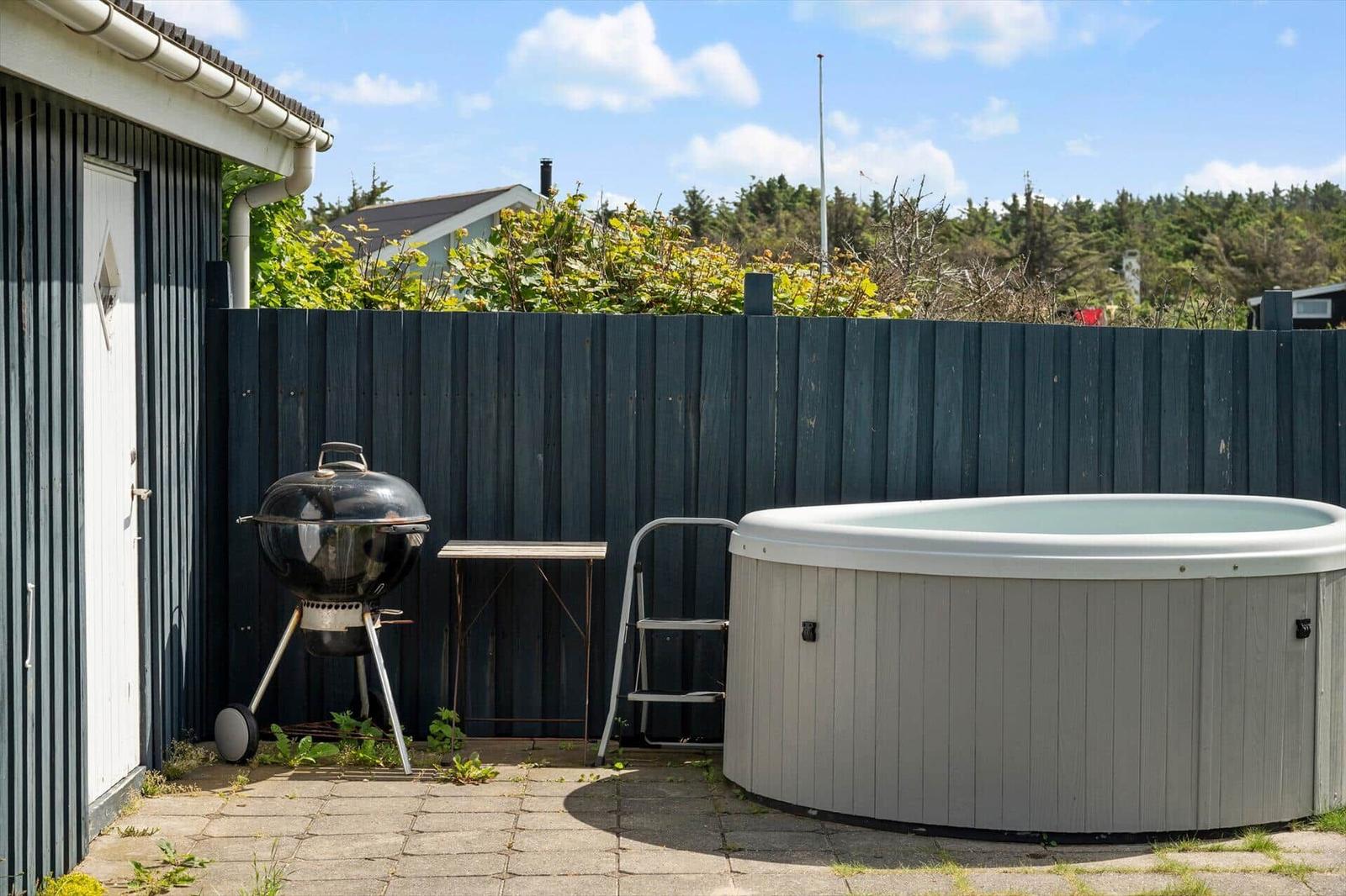 Hinterhof mit Whirlpool, Grill und Tisch neben einem Gebäude.