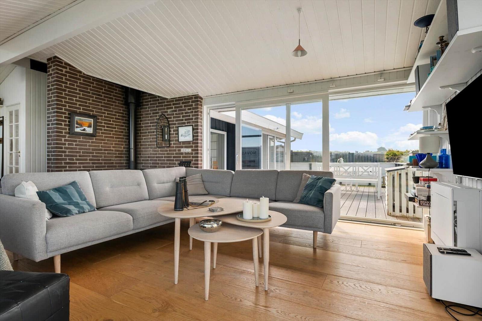 Wohnzimmer mit Sofa, Tisch und Terrasse. Holzboden und Backsteinwand.