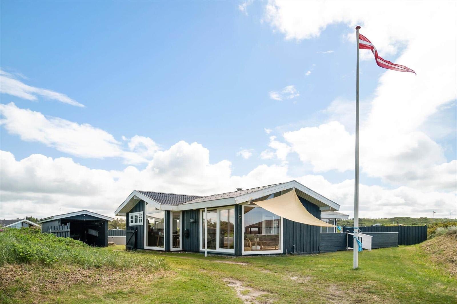 Moderne Strandvilla mit Flagge und Terrasse im Freien.