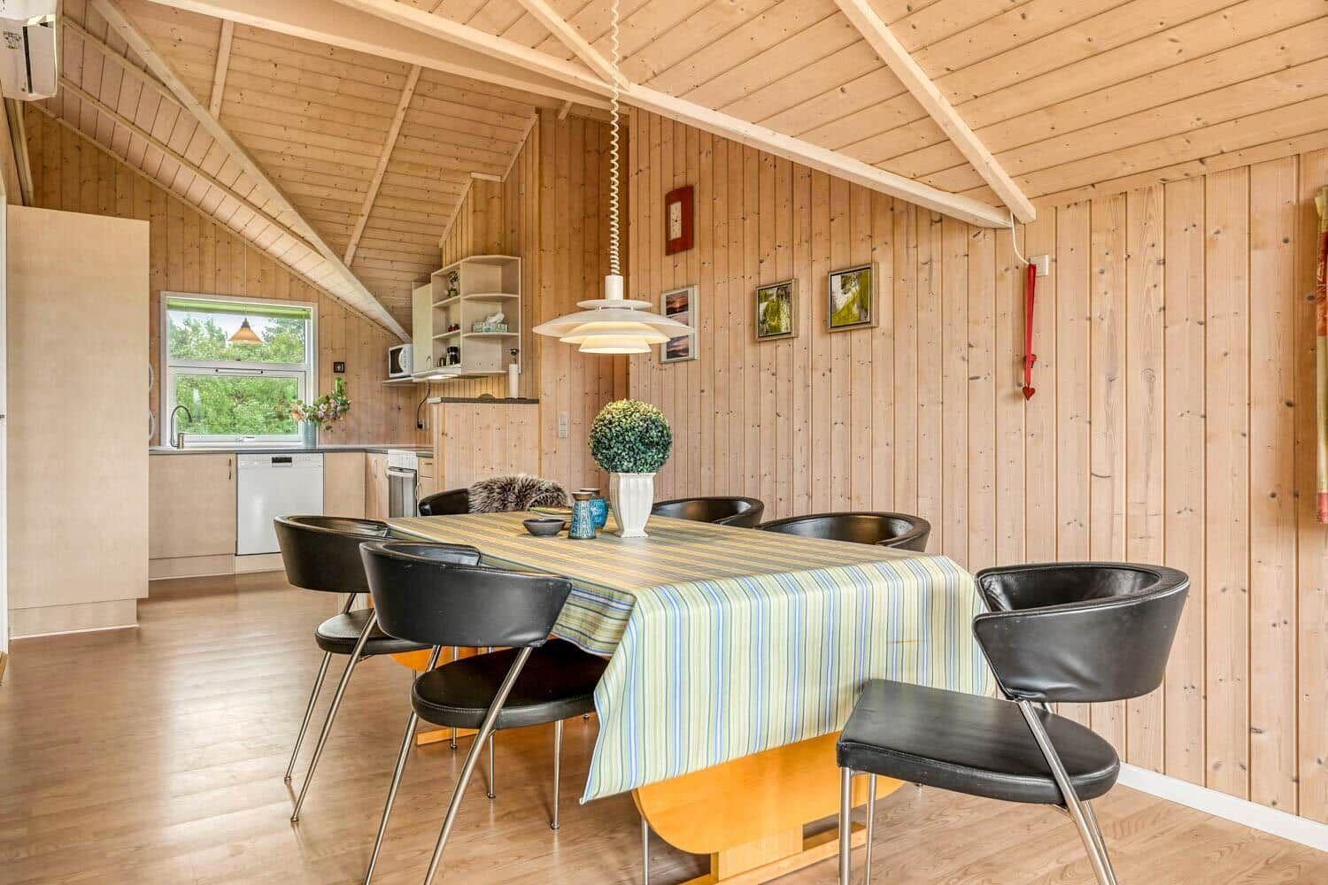 Essbereich mit Tisch, Stühlen und Küchenbereich in Holzhaus