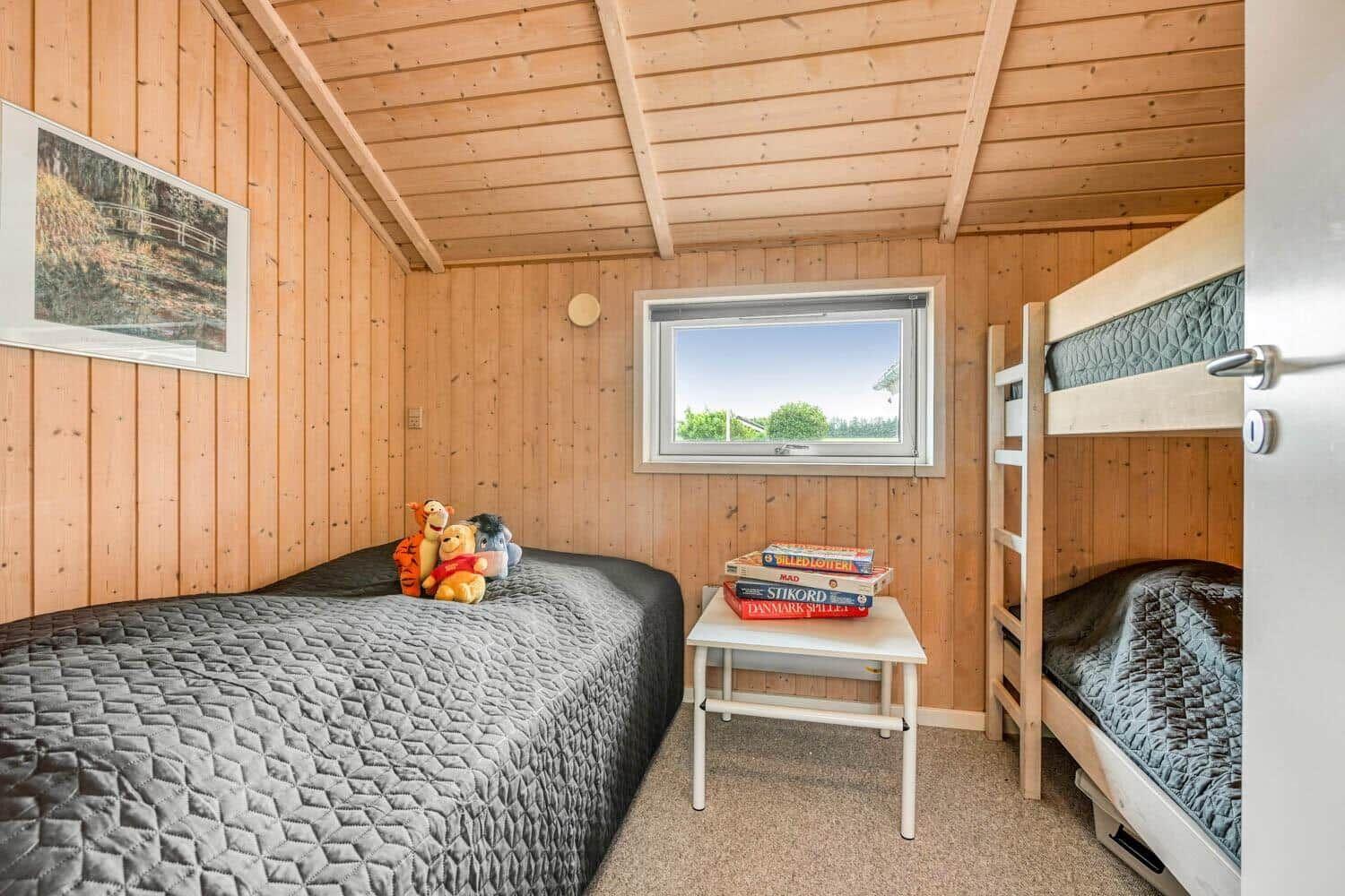 Ein Schlafzimmer mit Doppelbett, Etagenbett und Fenster. Auf dem Bett liegen Plüschtiere.