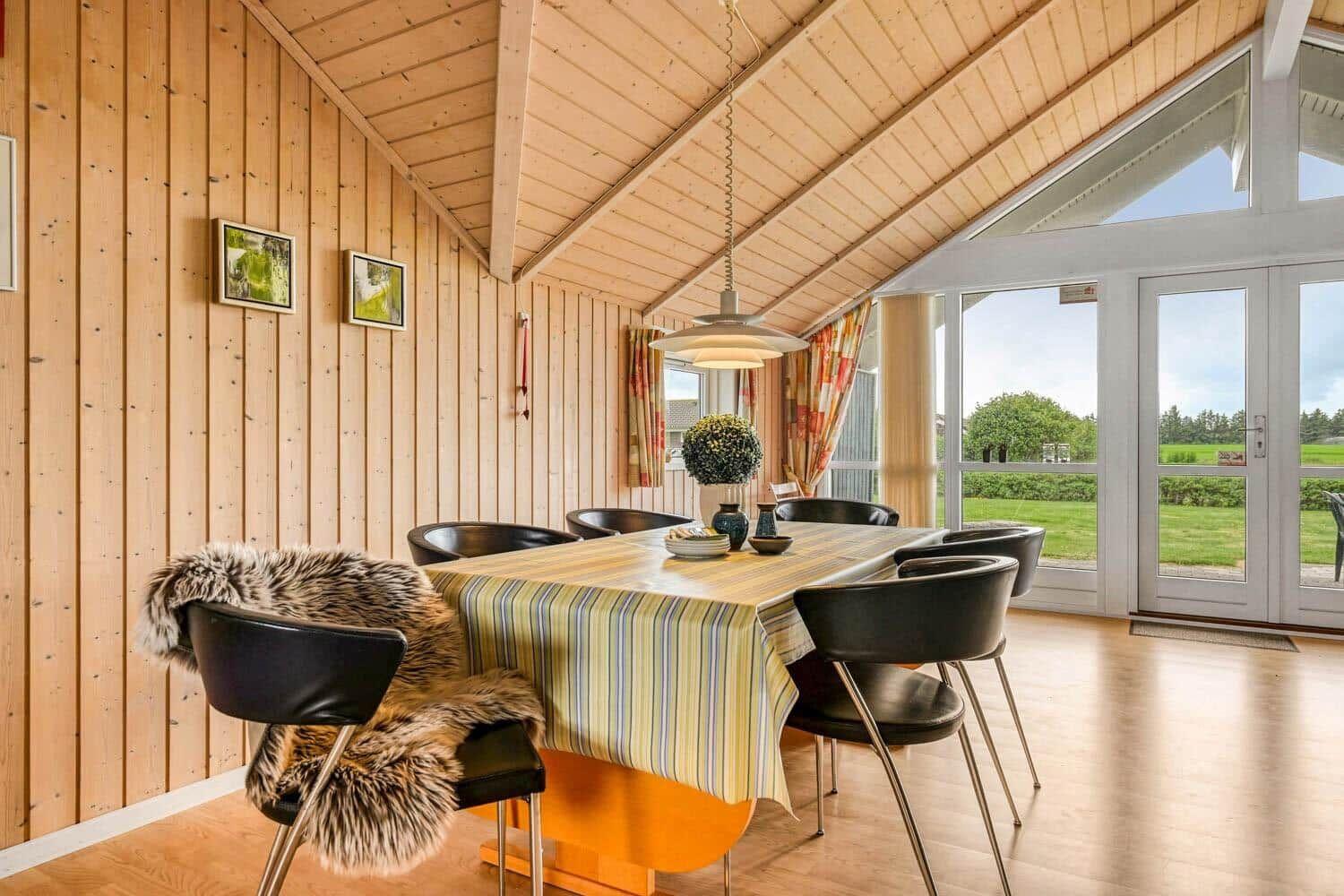 Esszimmer mit Holzwand, Tisch und Stühlen, Blick auf Garten
